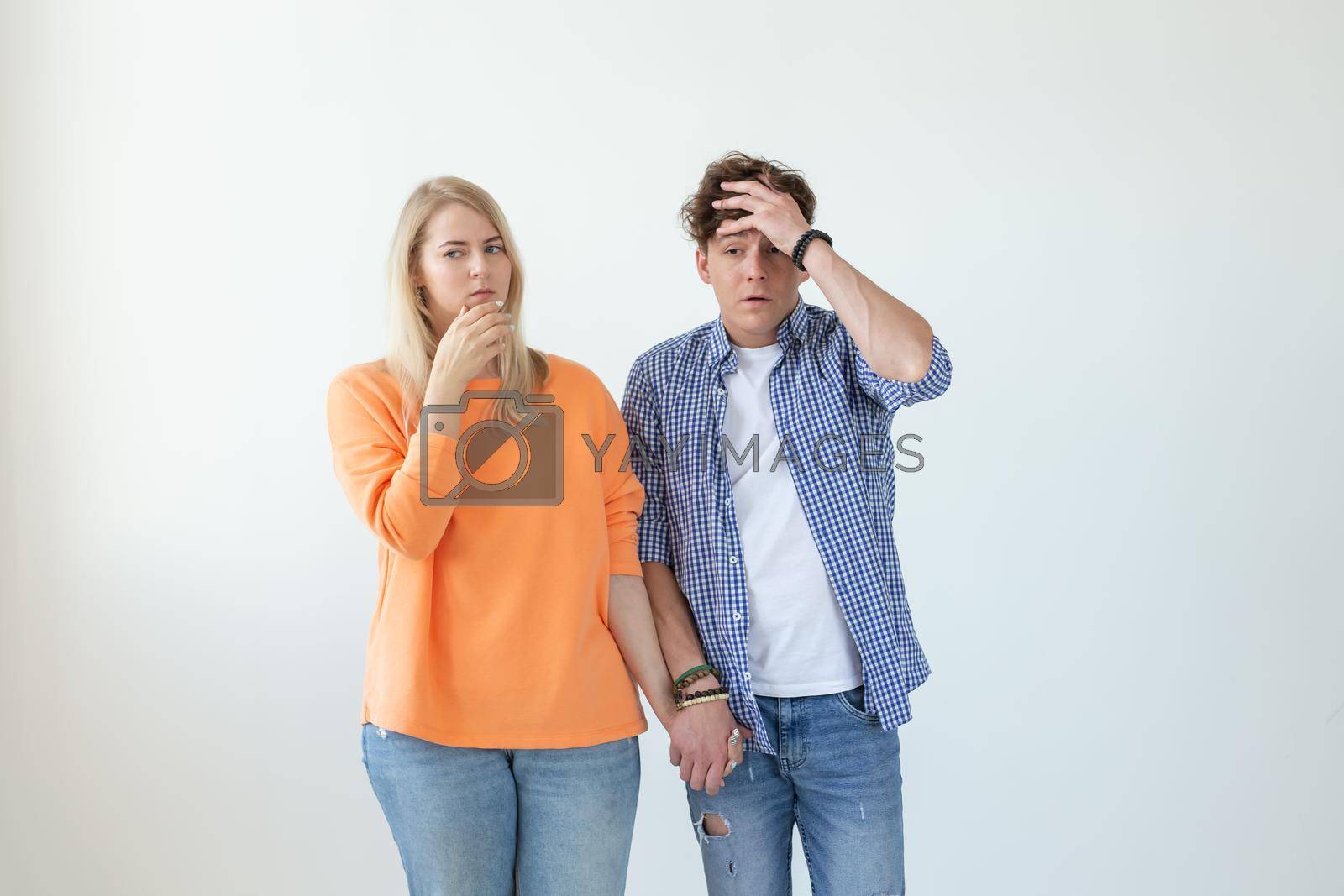 Royalty free image of Young couple of students disgruntled boyfriend and tired young girlfriend posing on a white background holding hands. Concept of a crisis in relationships and the help of a psychologist. by Satura86