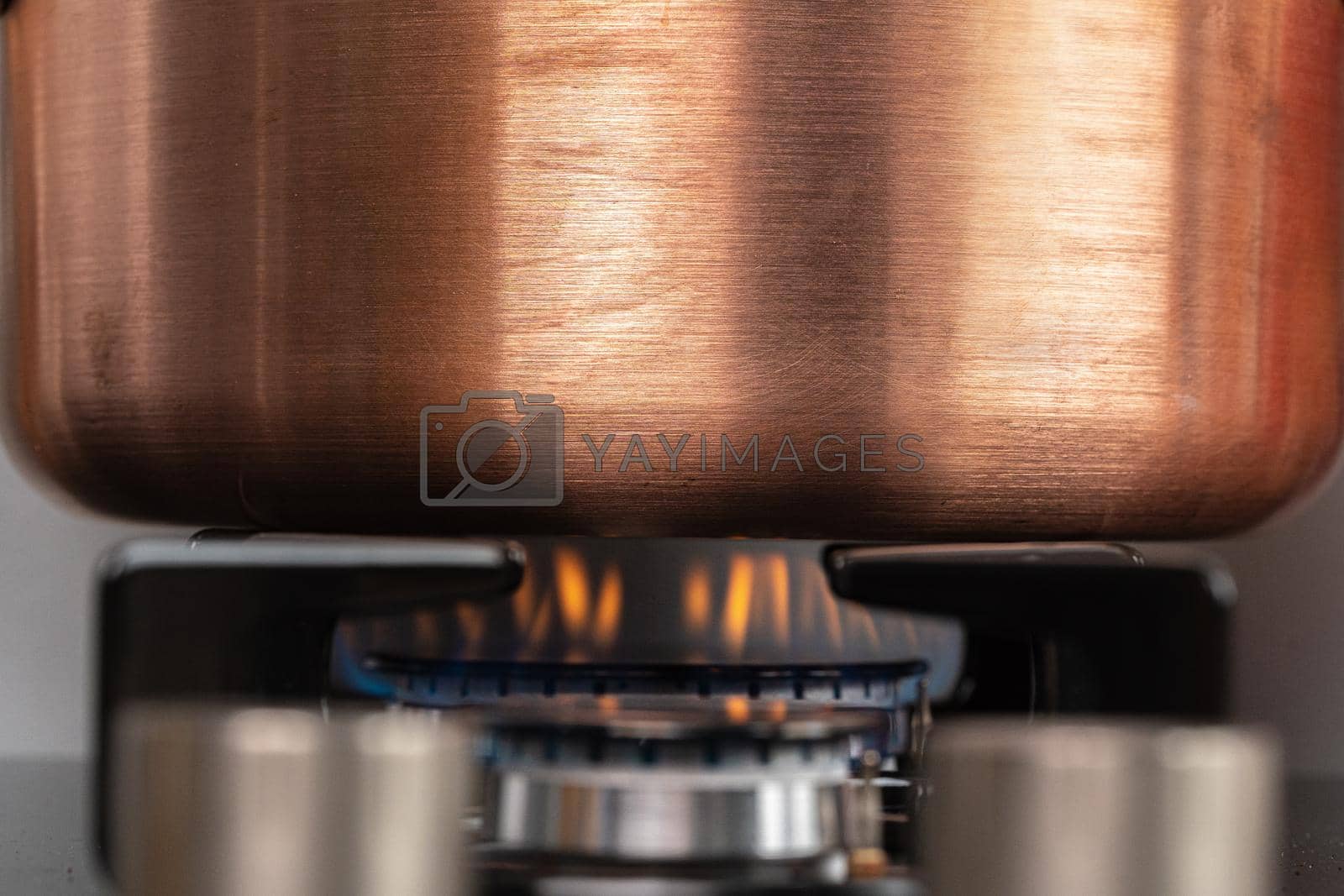 Royalty free image of Metal pot on a gas stove burner close up by Fabrikasimf