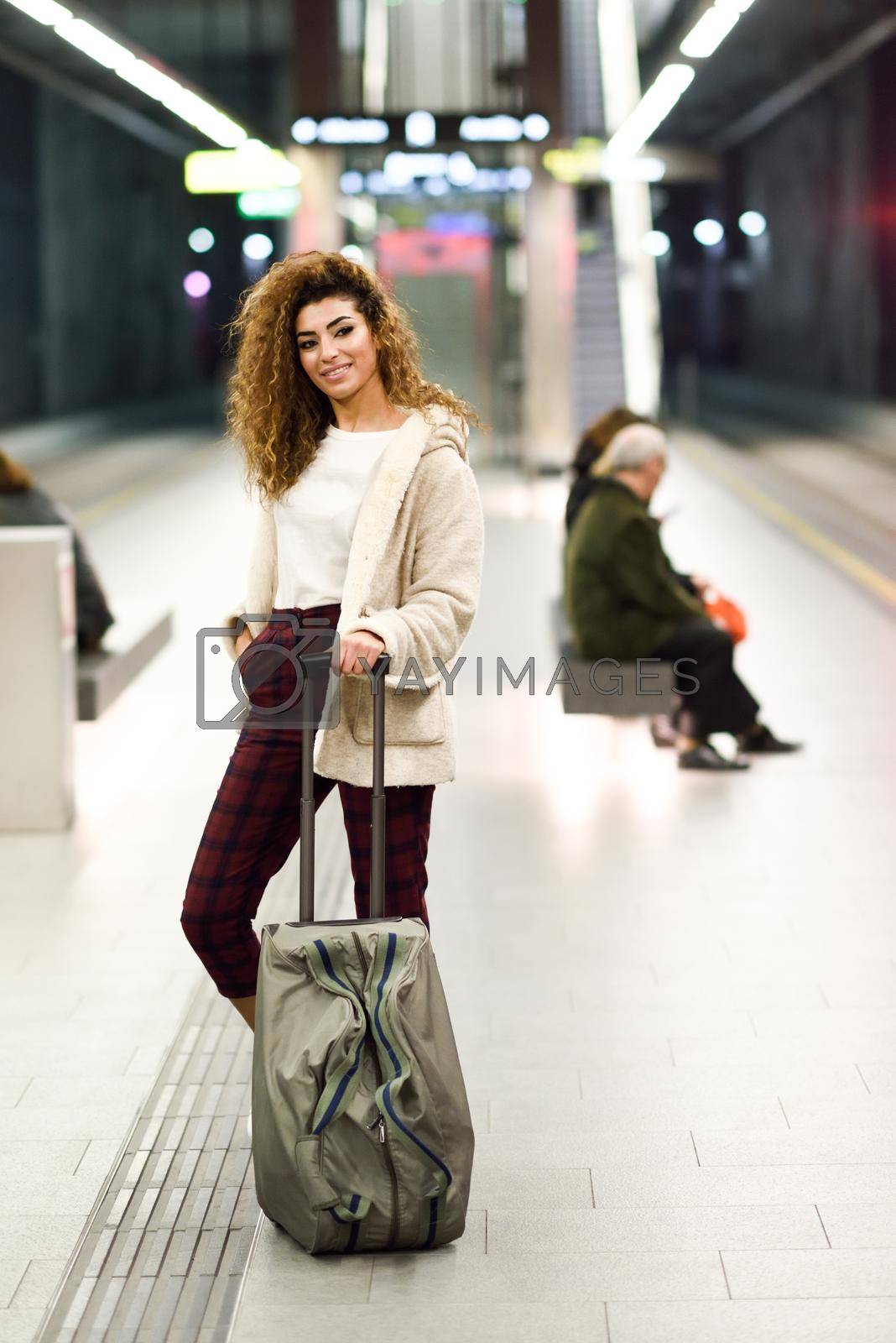 Beautiful young arabic woman waiting her train in a subway station. Arab traveler in casual clothes.