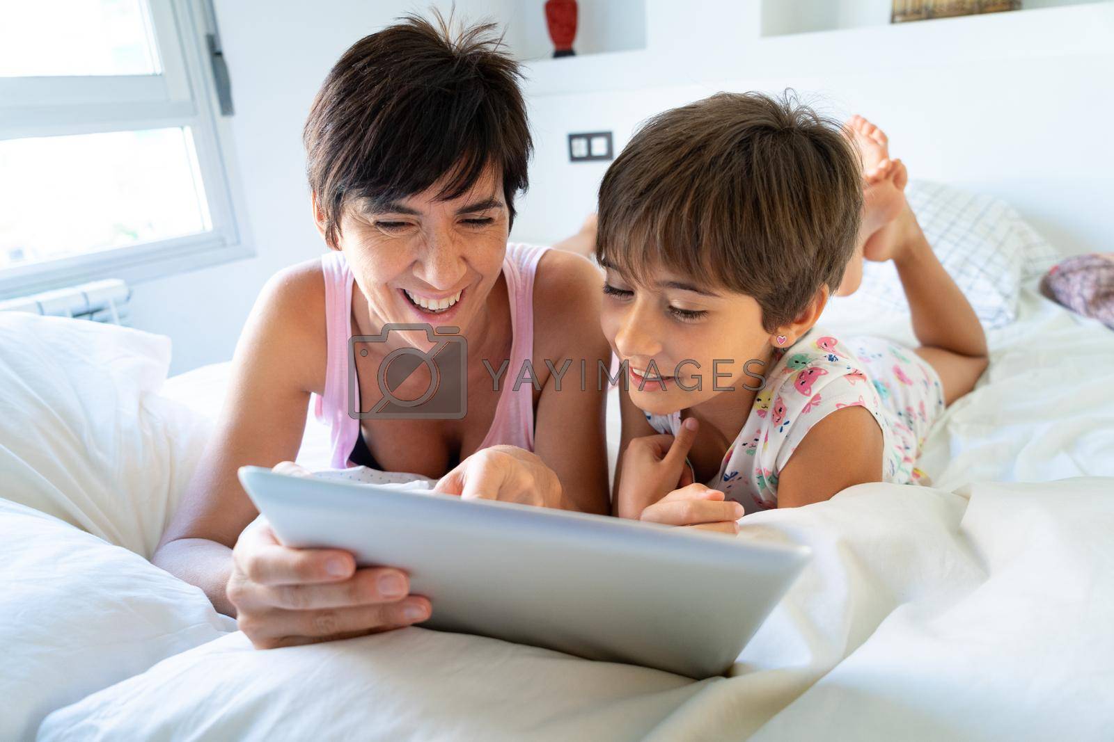 Royalty free image of Middle-age mother with her eight years daughter using digital tablet in bedroom. by javiindy