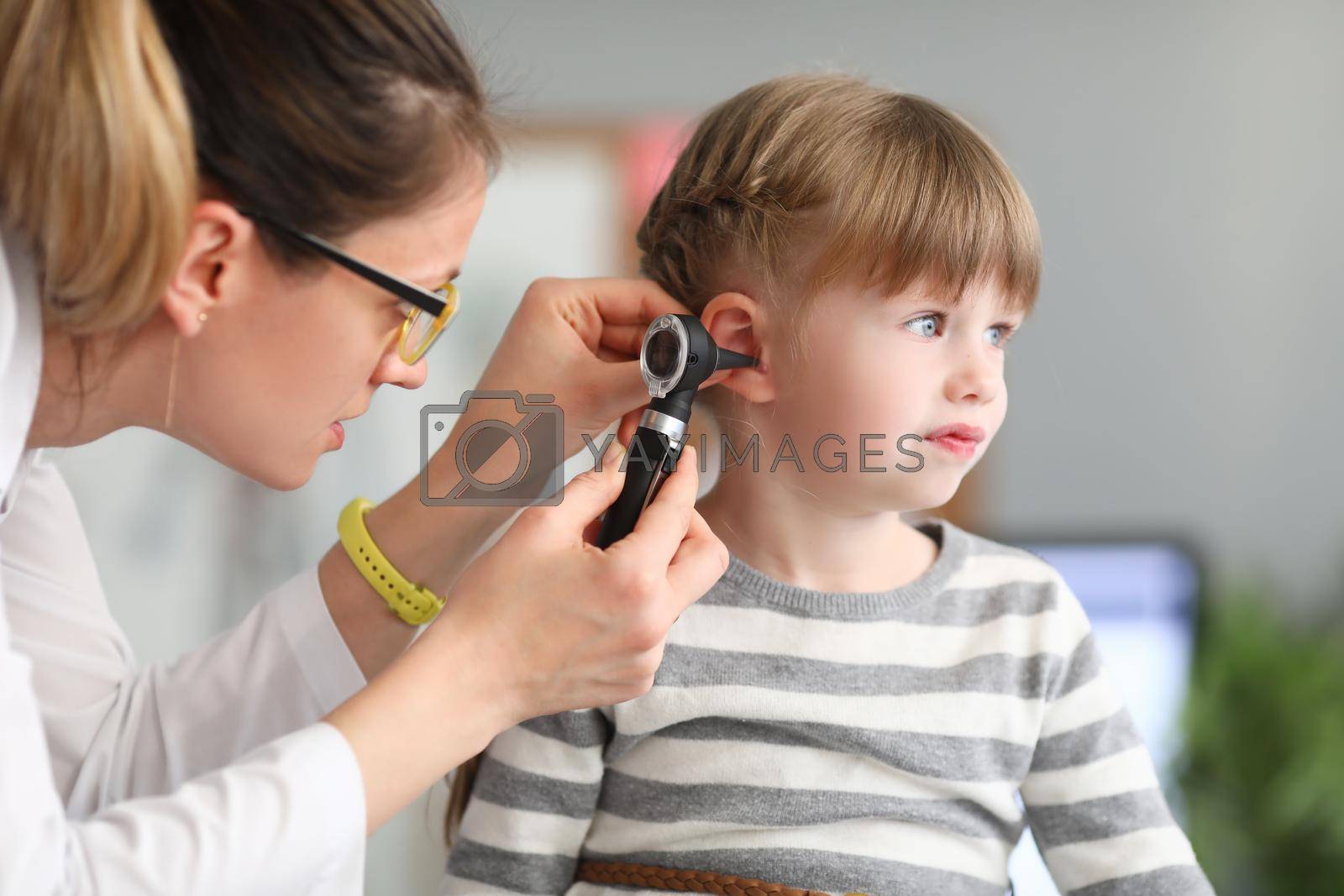 Royalty free image of ENT doctor conducts physical examination of little girl ear by kuprevich