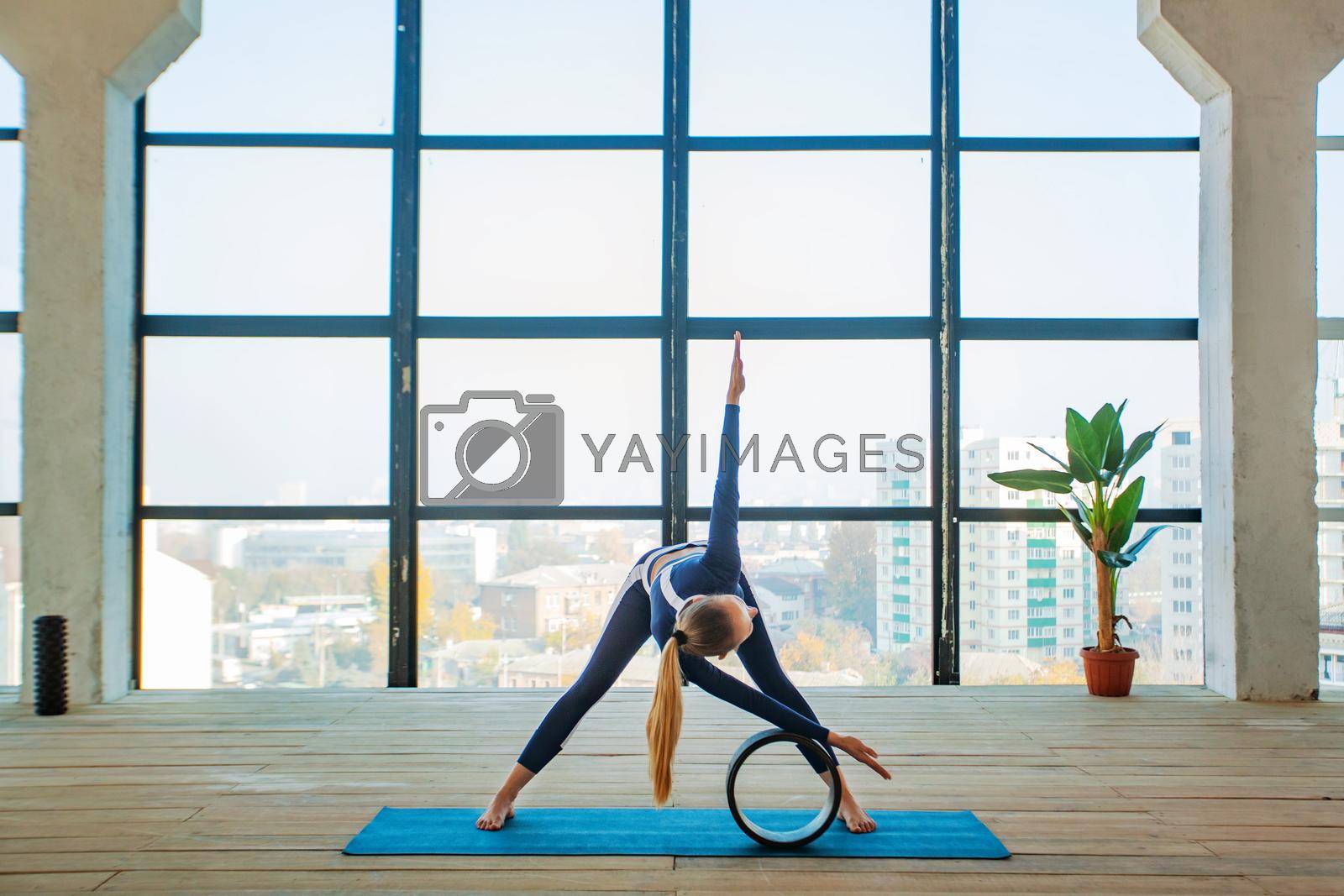Royalty free image of Yoga asana Indoor before a large panoramic window. Sports recreation. Beautiful young woman in yoga pose. Individual sports. by MikeOrlov