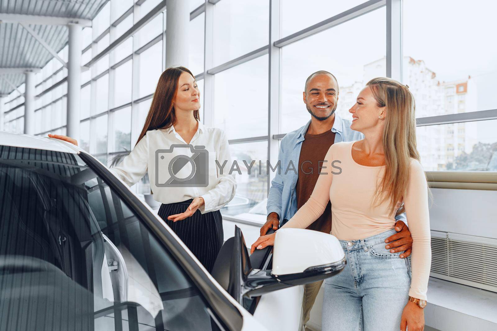 Royalty free image of Woman car dealer explaining to buyers features of their new car by Fabrikasimf