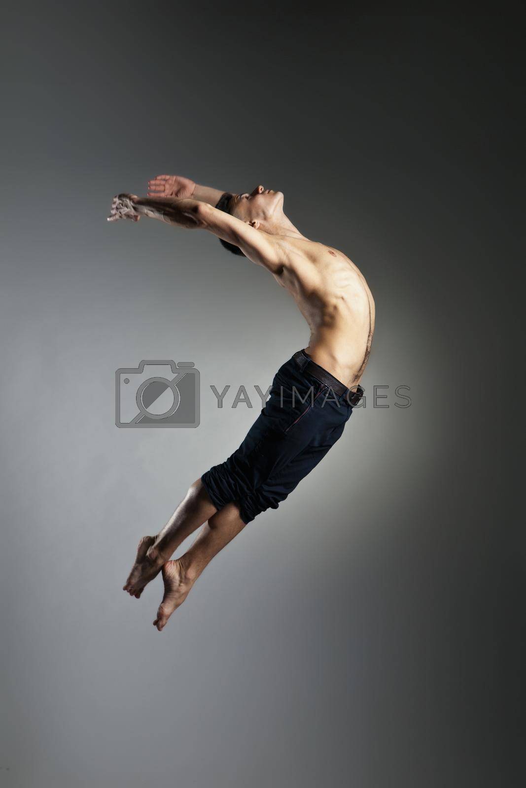 Royalty free image of Caucasian man gymnastic leap posture on grey by Julenochek