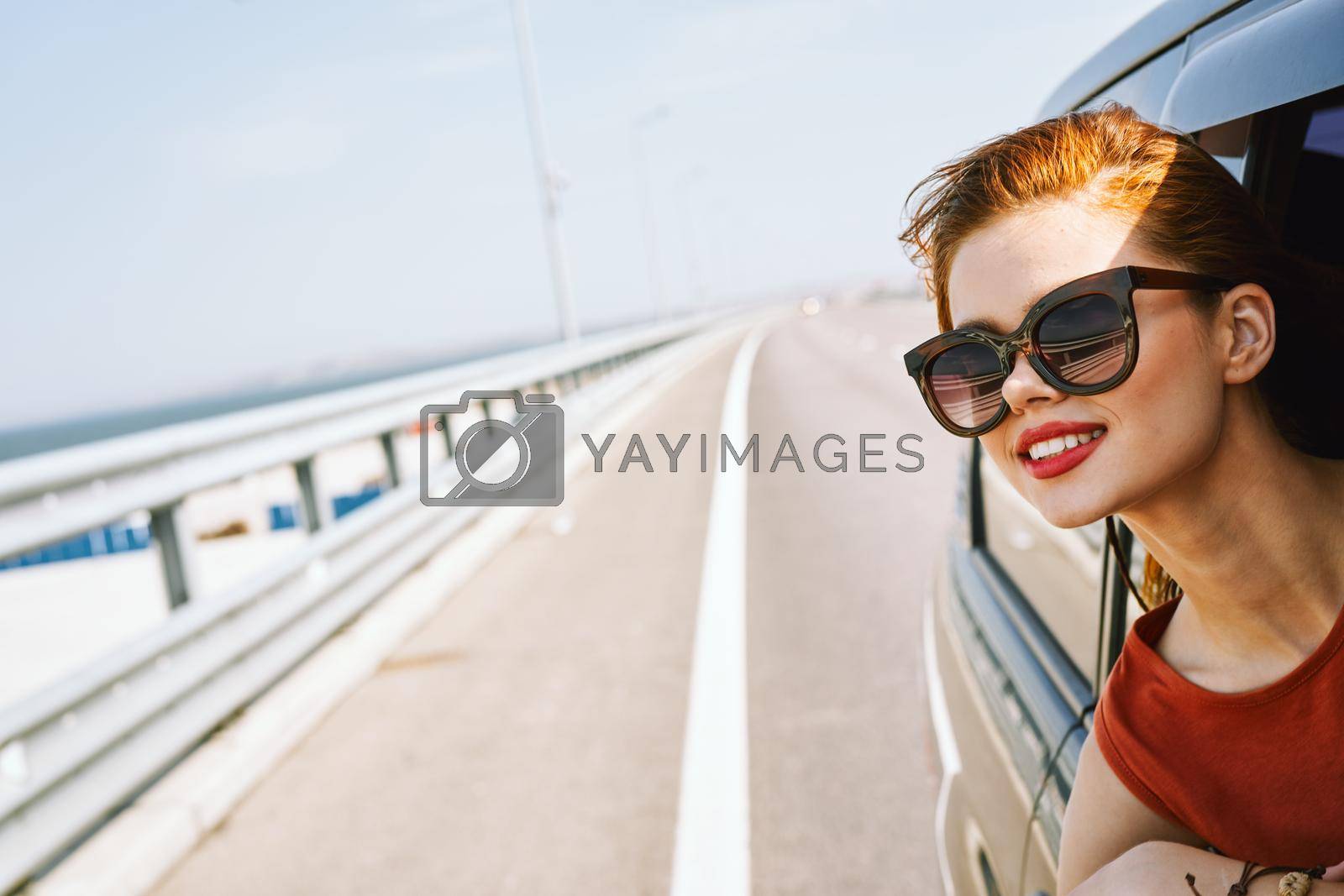 cheerful woman peeking out of the car window trip adventure lifestyle. High quality photo
