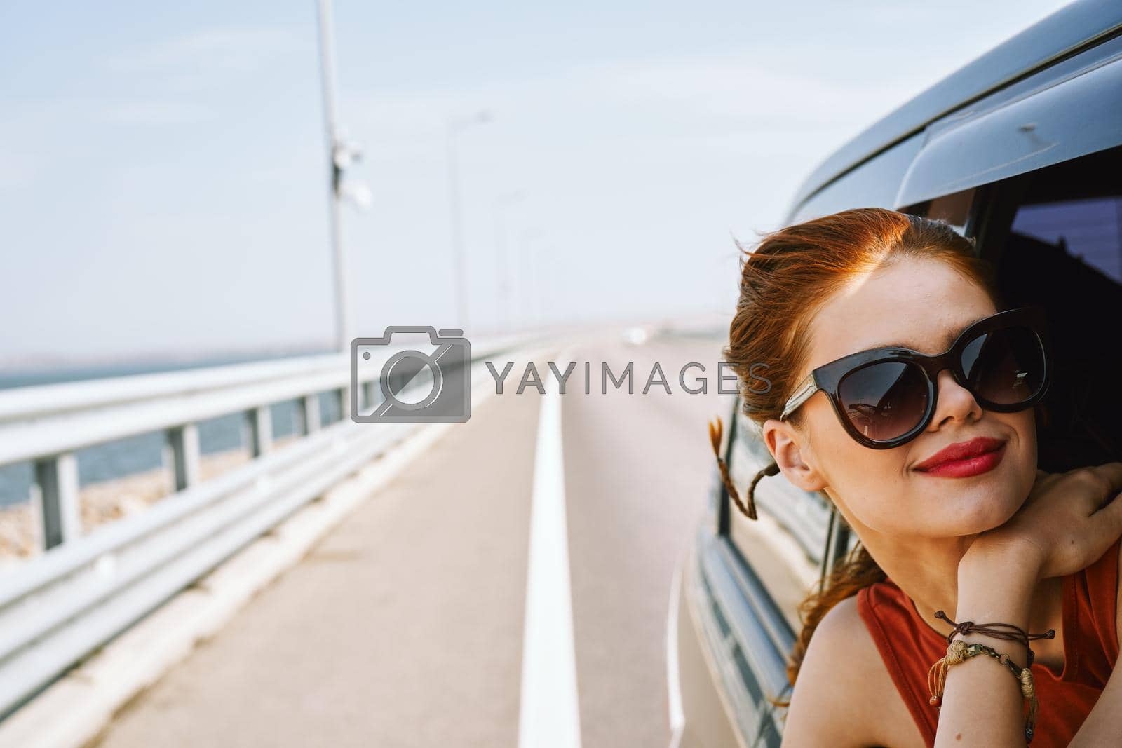Royalty free image of pretty woman in sunglasses rides in a travel car by Vichizh