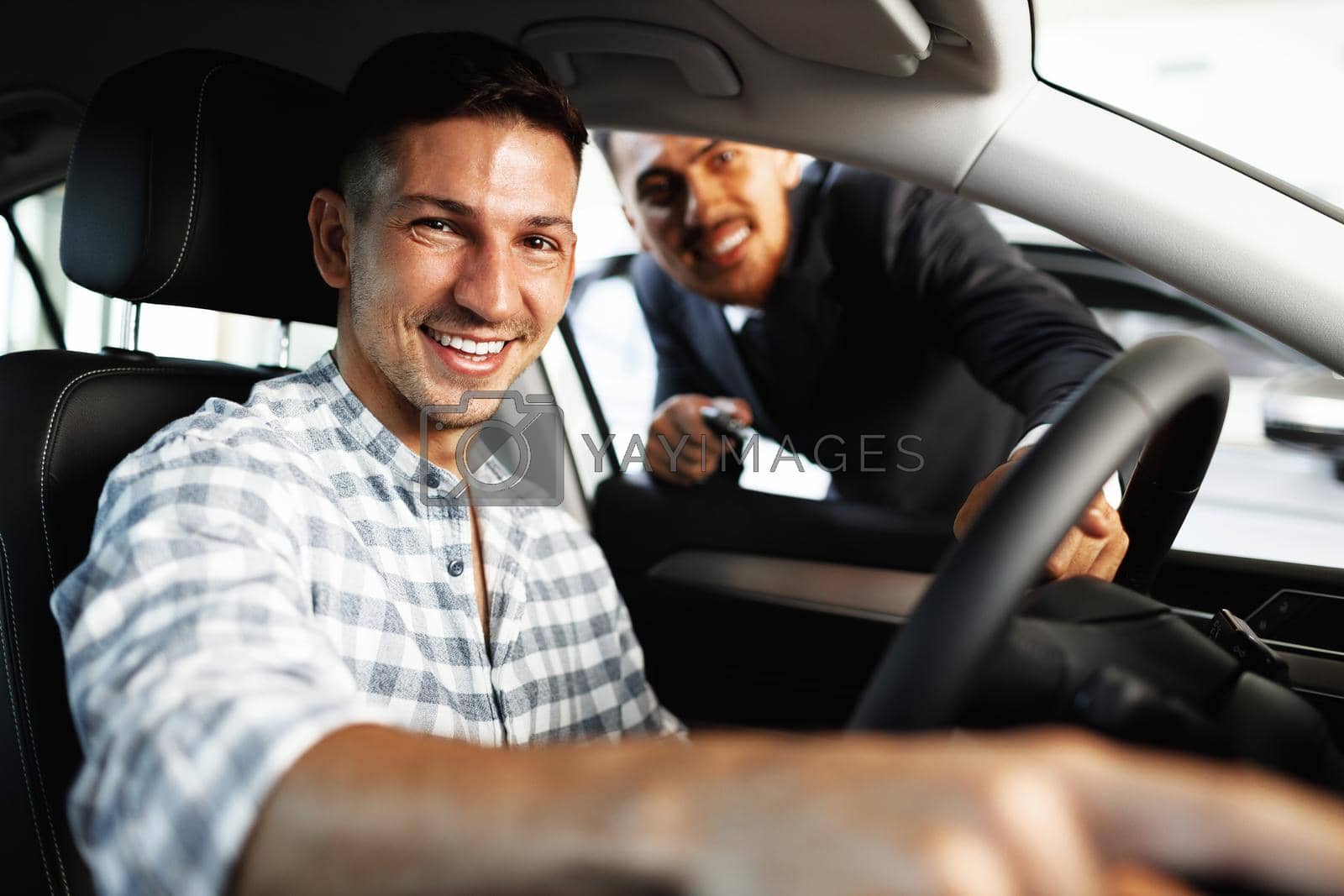 Royalty free image of Cheerful young man customer buys a new car in a dealership by Fabrikasimf