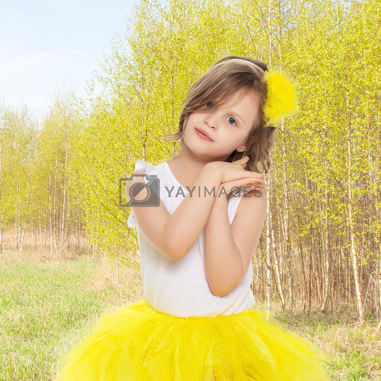 Royalty free image of Little girl in a yellow skirt and white t-shirt. by kolesnikov_studio