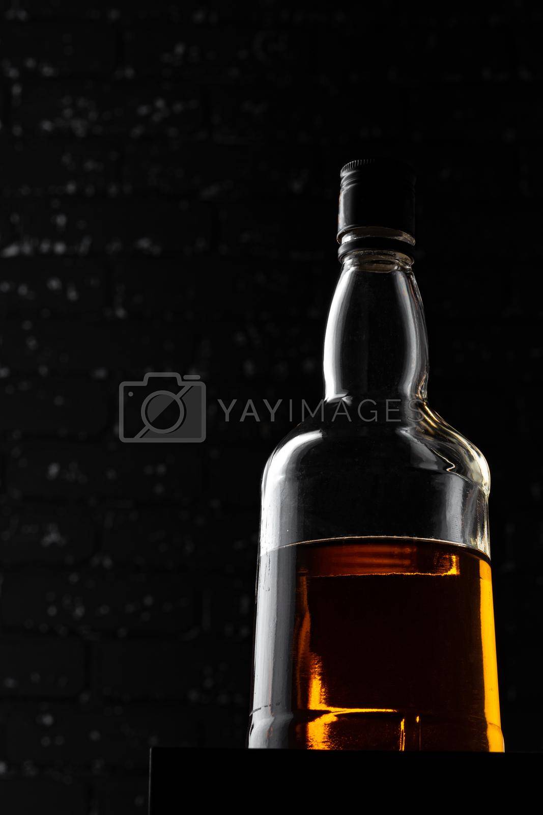 Royalty free image of Whisky bottle close up against black grunge wall by Fabrikasimf