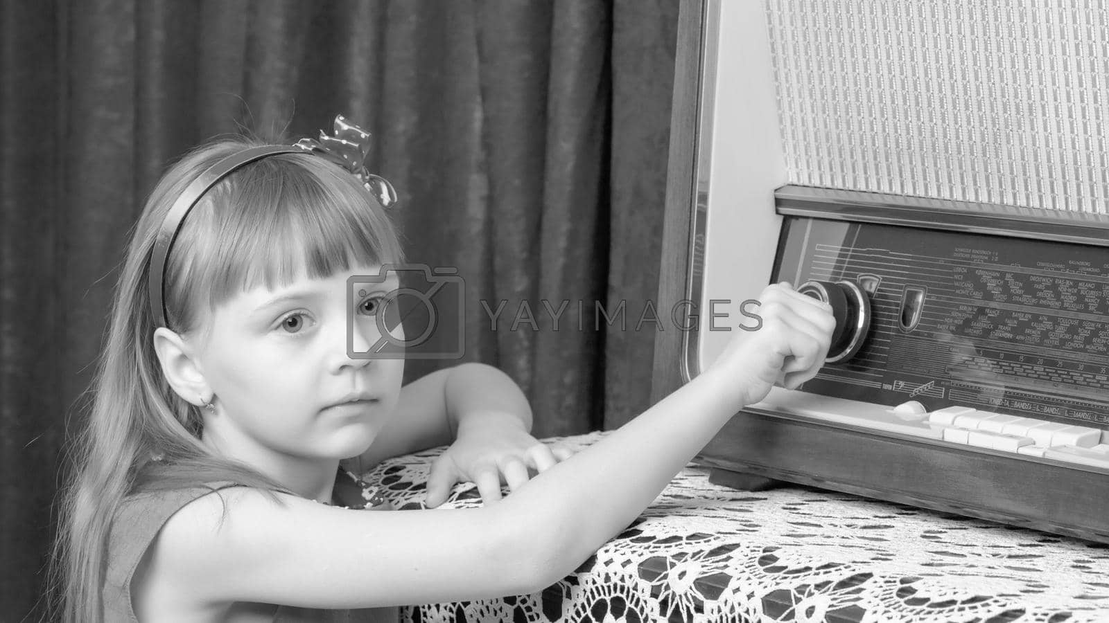 Royalty free image of The girl turns the volume knob on the old radio. Retro style. by kolesnikov_studio