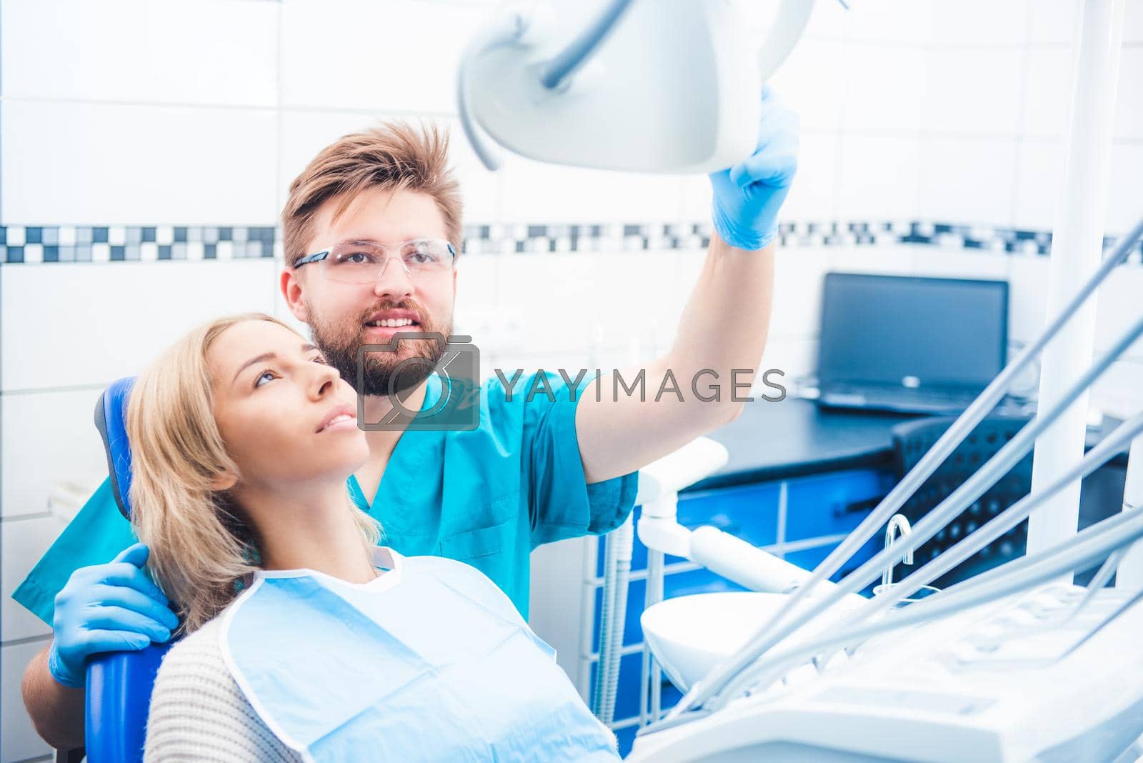 Dentist holding special lamp examinating patient in dentistry