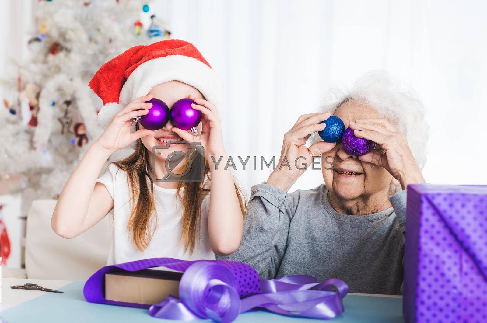 Royalty free image of Granddaughter holding decorative balls with grandma by GekaSkr