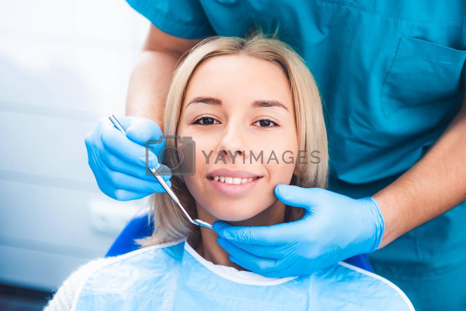 Dentist examinating blond girl with tools