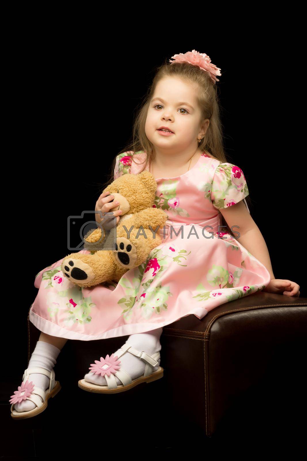 Royalty free image of Little girl with a teddy bear on a black background. by kolesnikov_studio