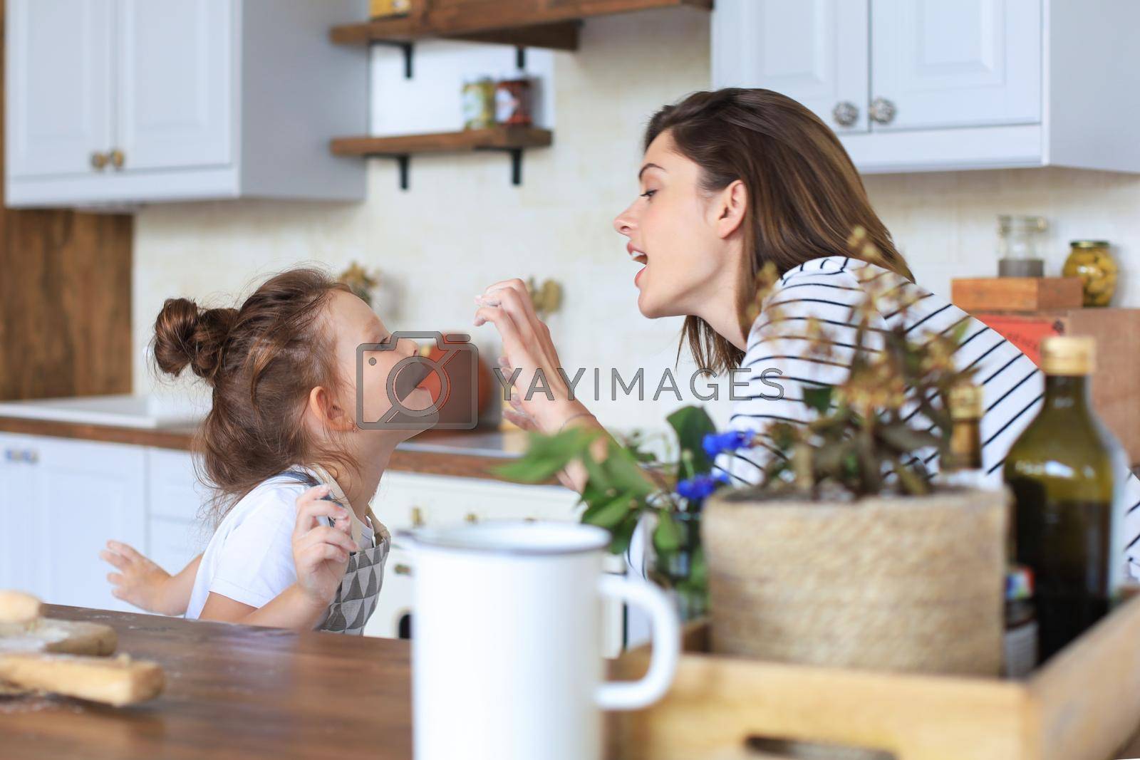 Royalty free image of Playful little girl cooking at kitchen with her loving mother. by tsyhun