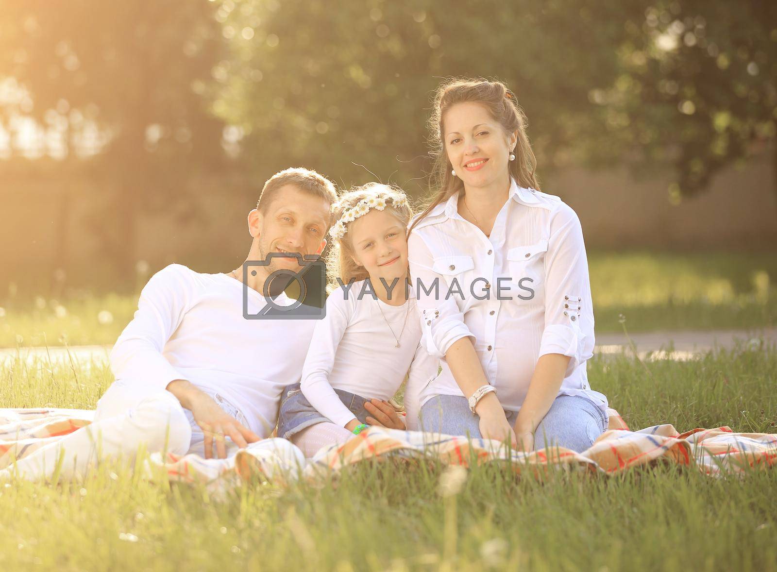 pregnant mother,happy father and daughter on a picnic in the Park on Sunday