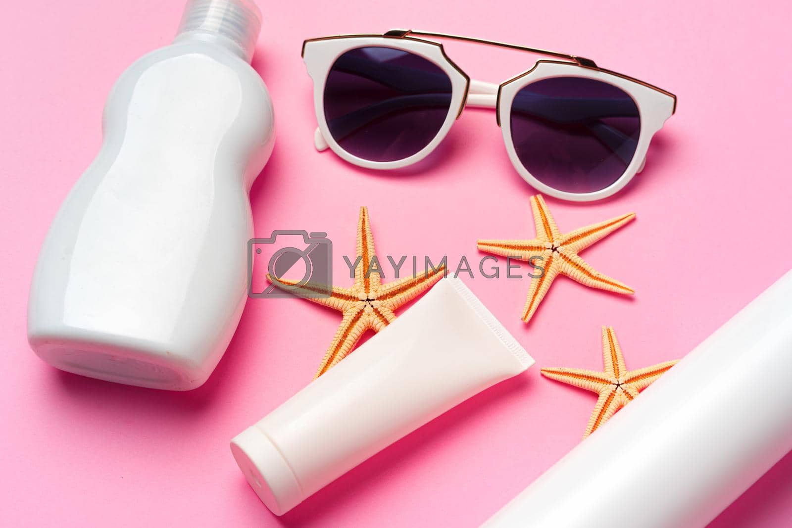 Royalty free image of Sunglasses and sunblock cream close up on paper background by Fabrikasimf