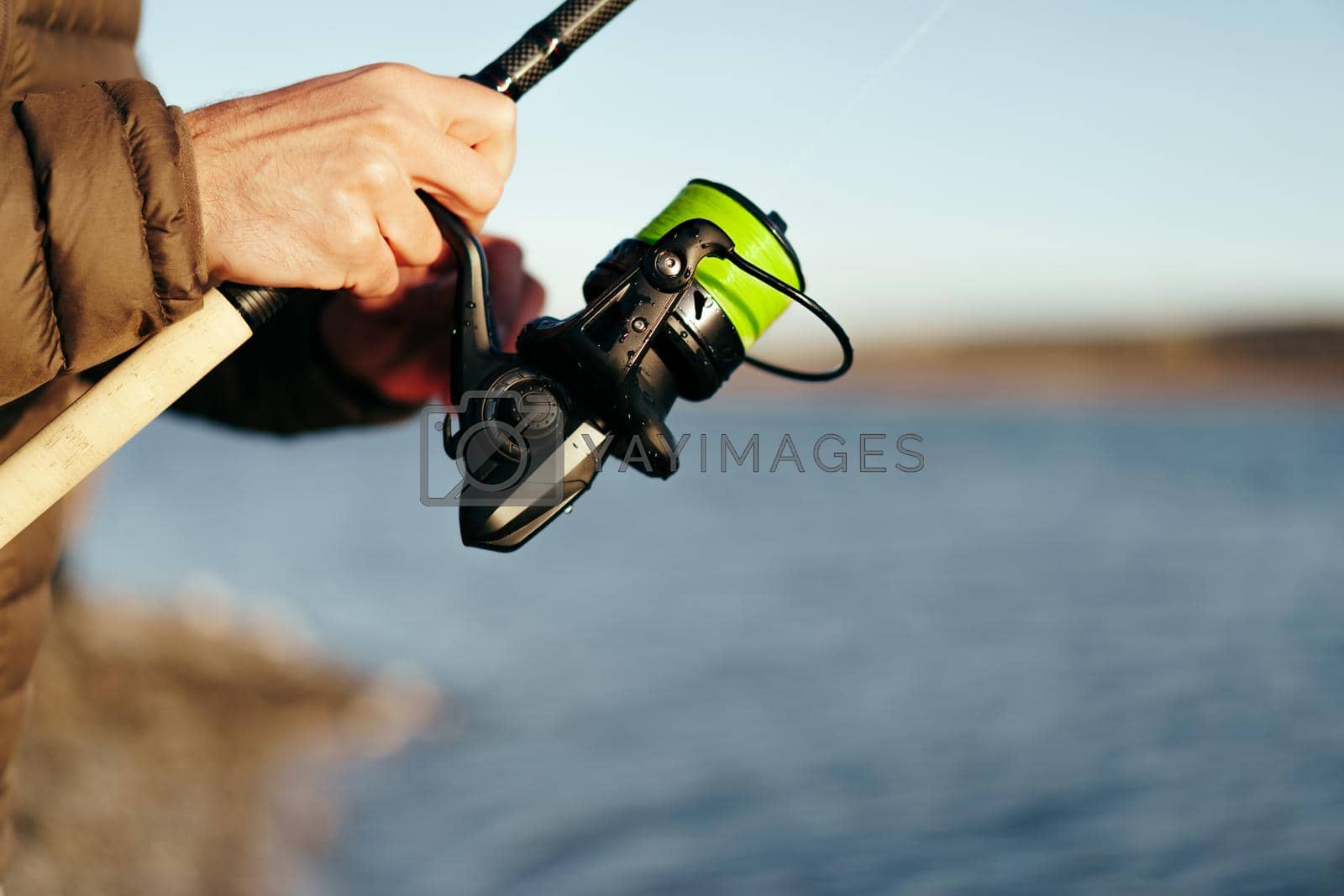 Royalty free image of Fisherman hands holding fishing rod close up by Fabrikasimf
