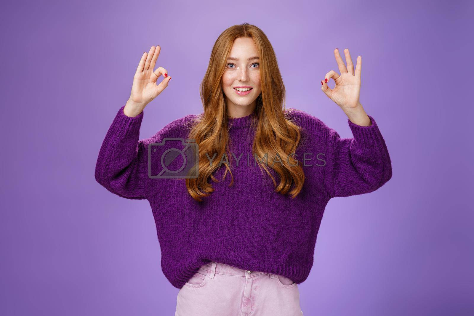 Royalty free image of Fine I agree. Portrait of friendly and optimstic young 20s ginger girl in purple sweater raising hands with okay or ok gesture smiling in approval, liking cool product, giving recommendation by Benzoix