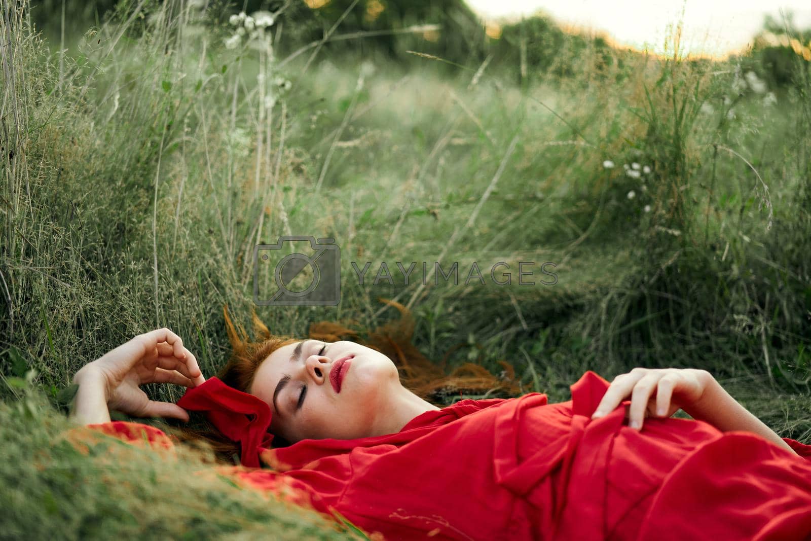 woman in red dress lying on the grass fresh air nature romance. High quality photo