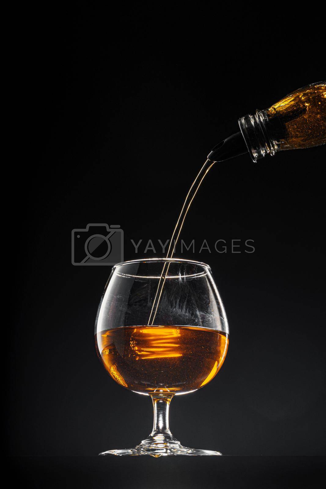 Royalty free image of Whisky pouring into a glass on black background by Fabrikasimf