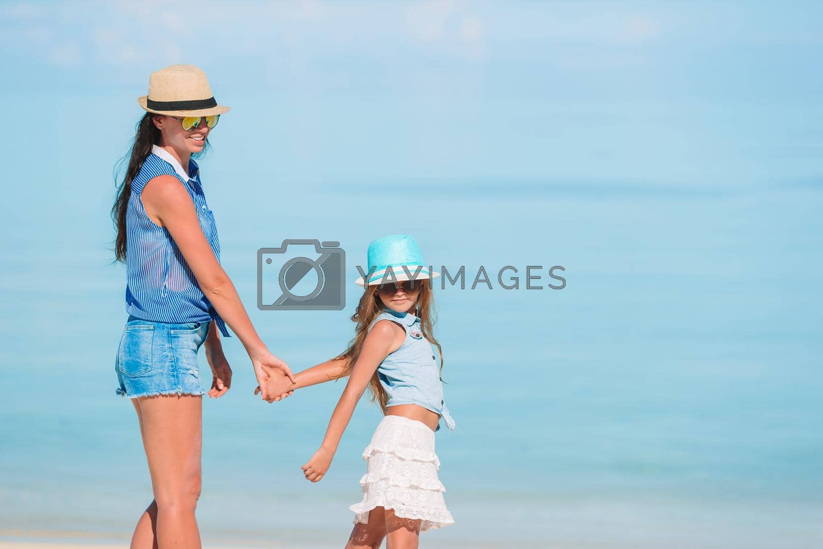 Young beautiful mother and her adorable little daughter on tropical beach