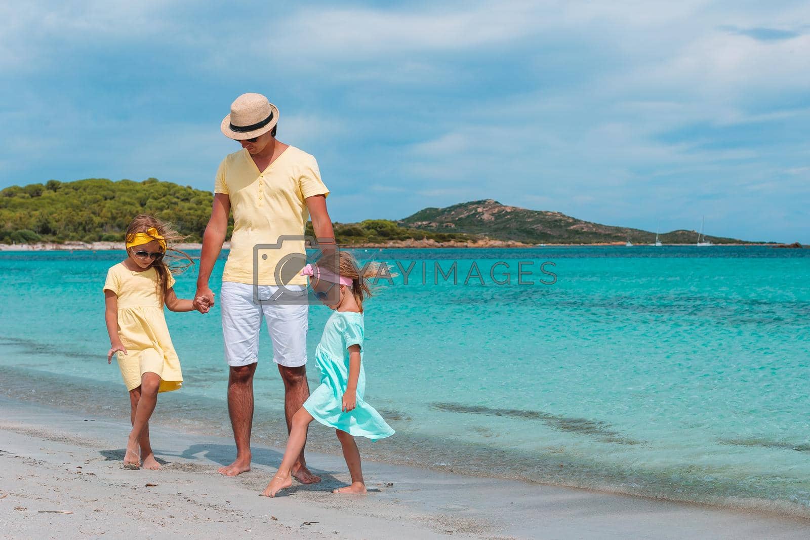 Royalty free image of Father and two daughters on Caribbean beach by travnikovstudio