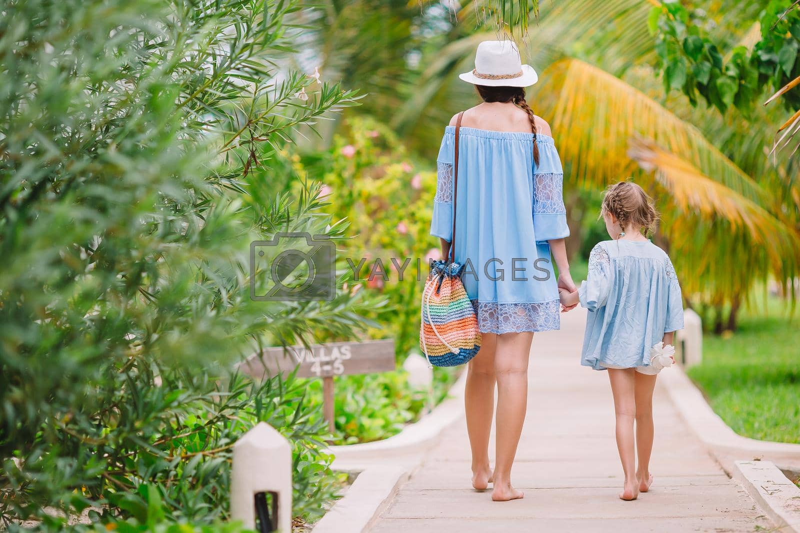 Young beautiful mother and her adorable little daughter walking at luxury resort