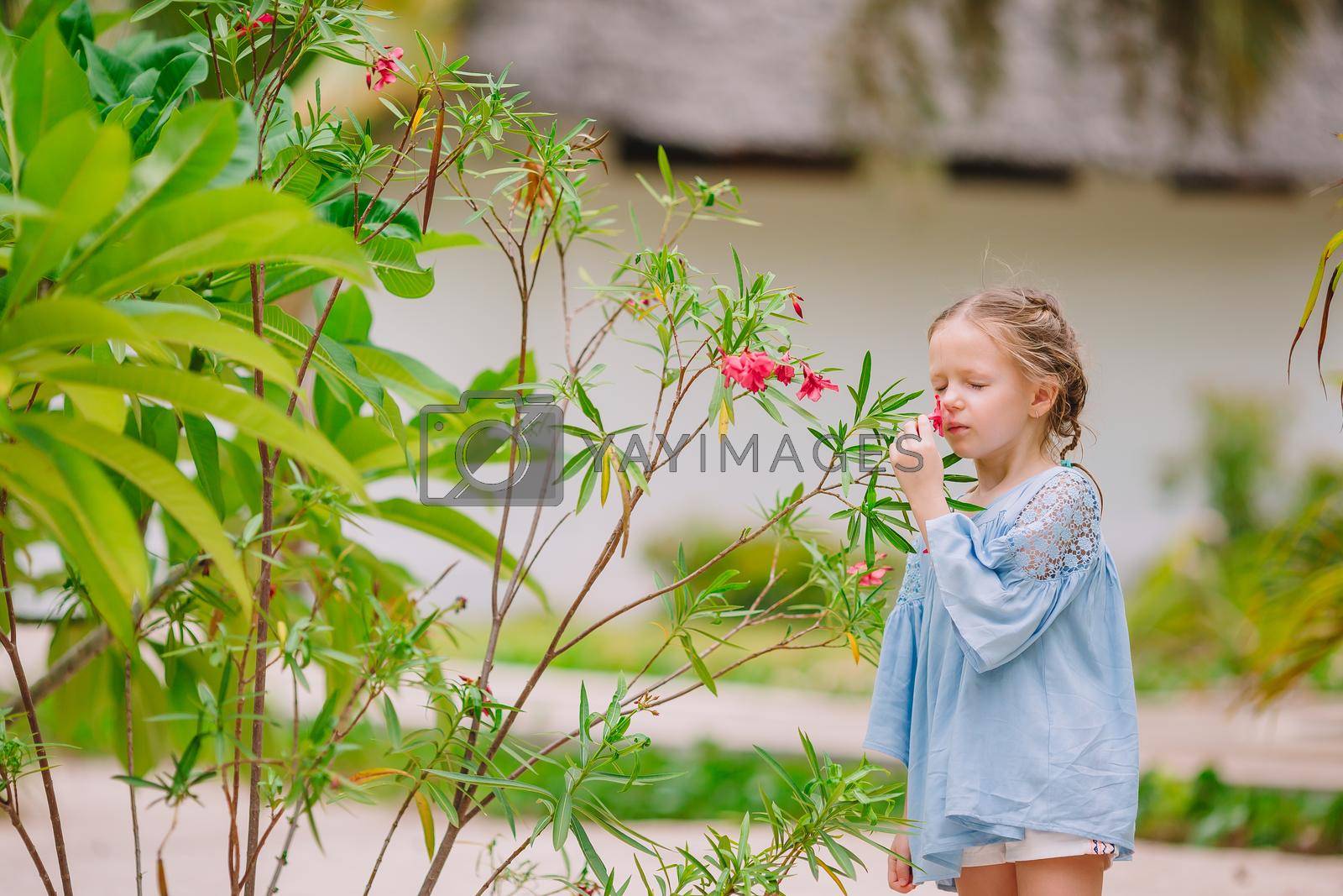 Royalty free image of Little adorable girl smelling colorful flowers at summer day by travnikovstudio