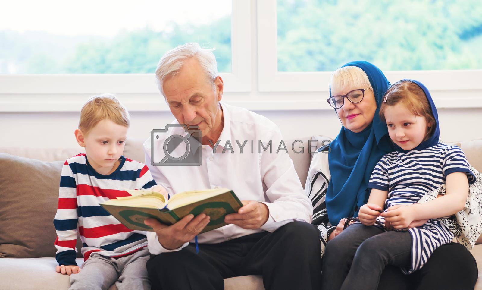 Royalty free image of modern muslim grandparents with grandchildren reading Quran by dotshock