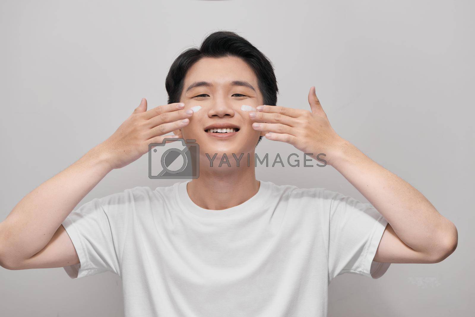 Royalty free image of smiling man applying cream lotion on face by makidotvn