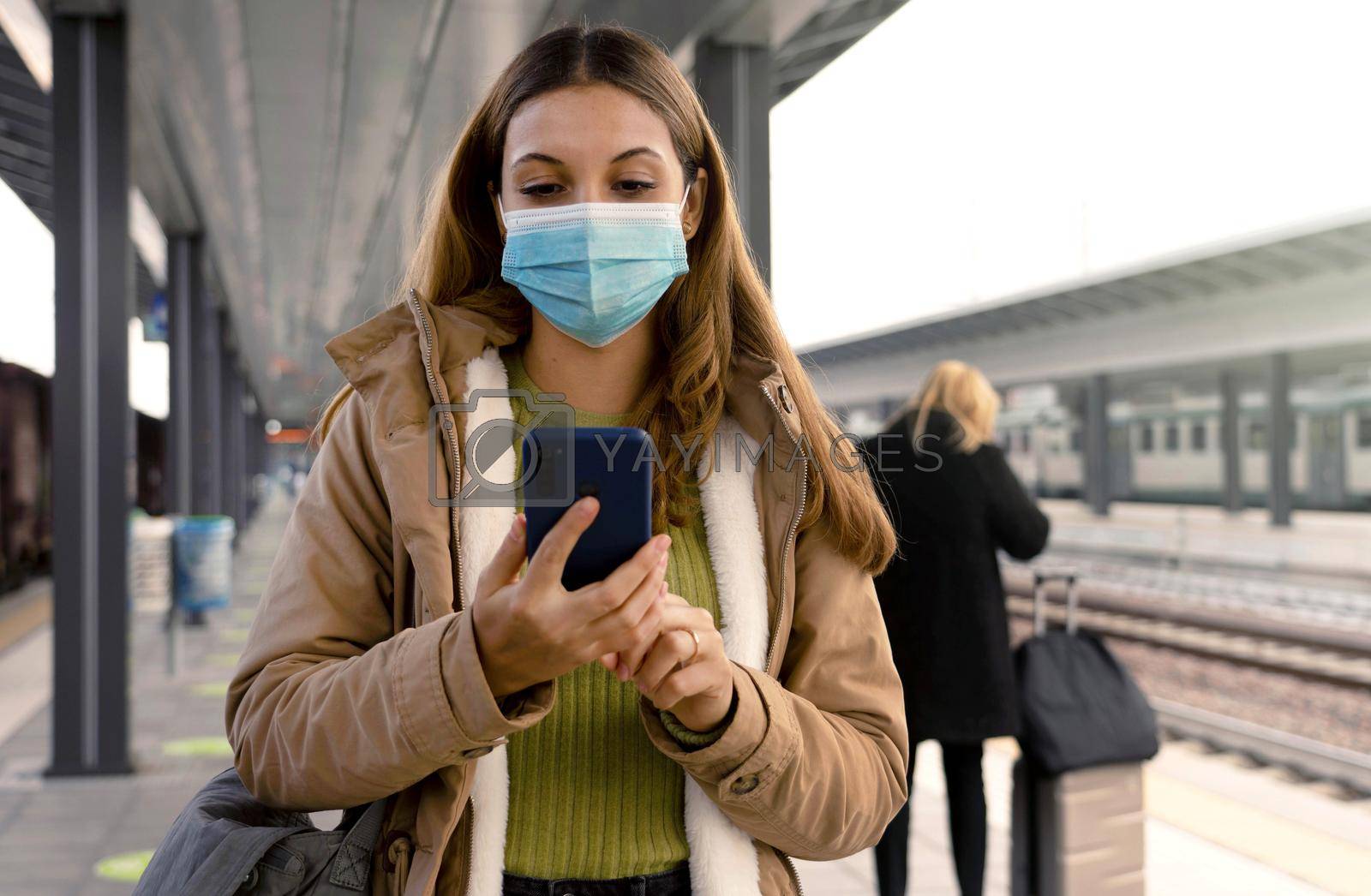 People with surgical mask using smartphone at train station