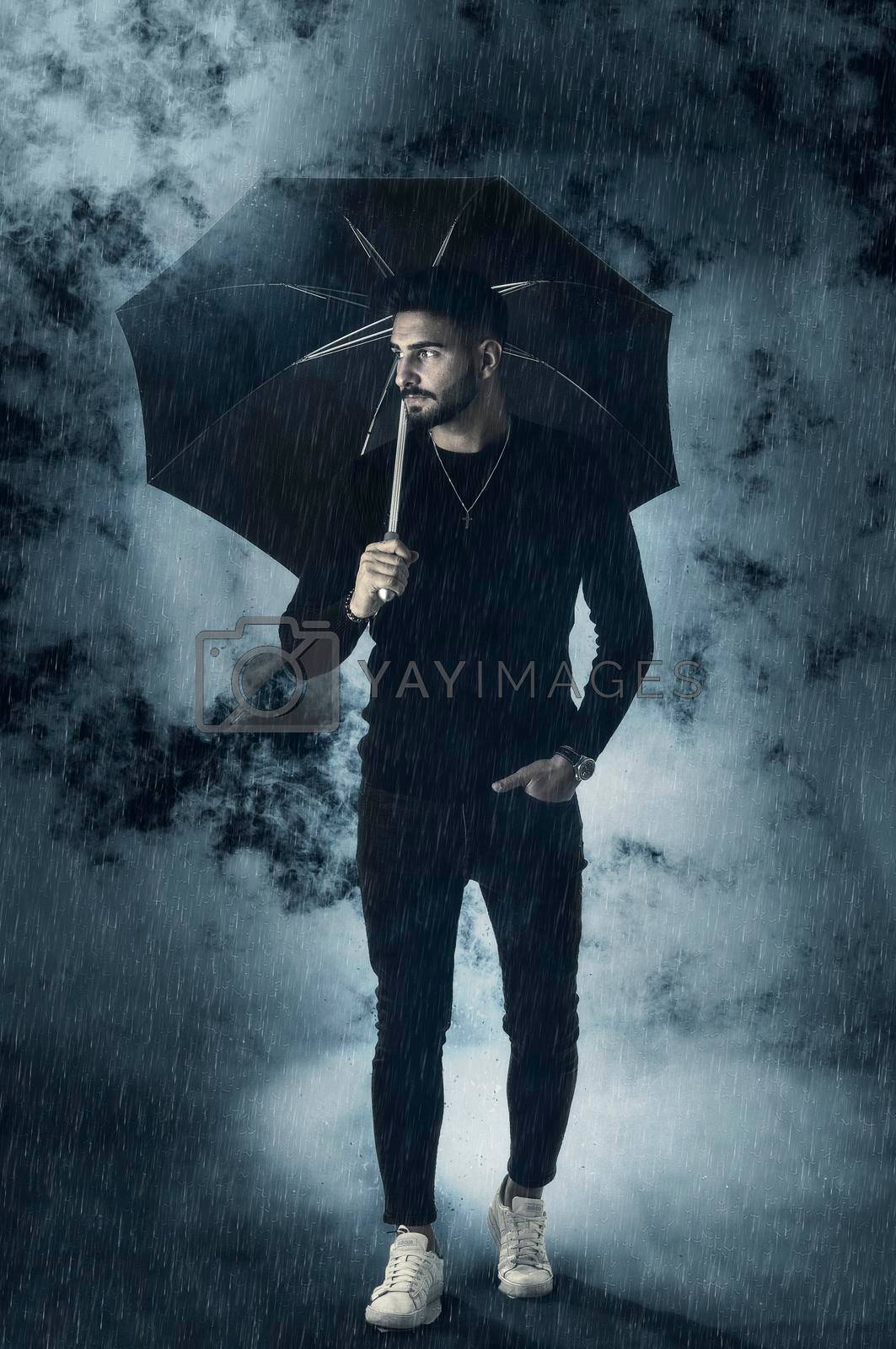 Royalty free image of Young man under an umbrella, with rain and fog around by artofphoto