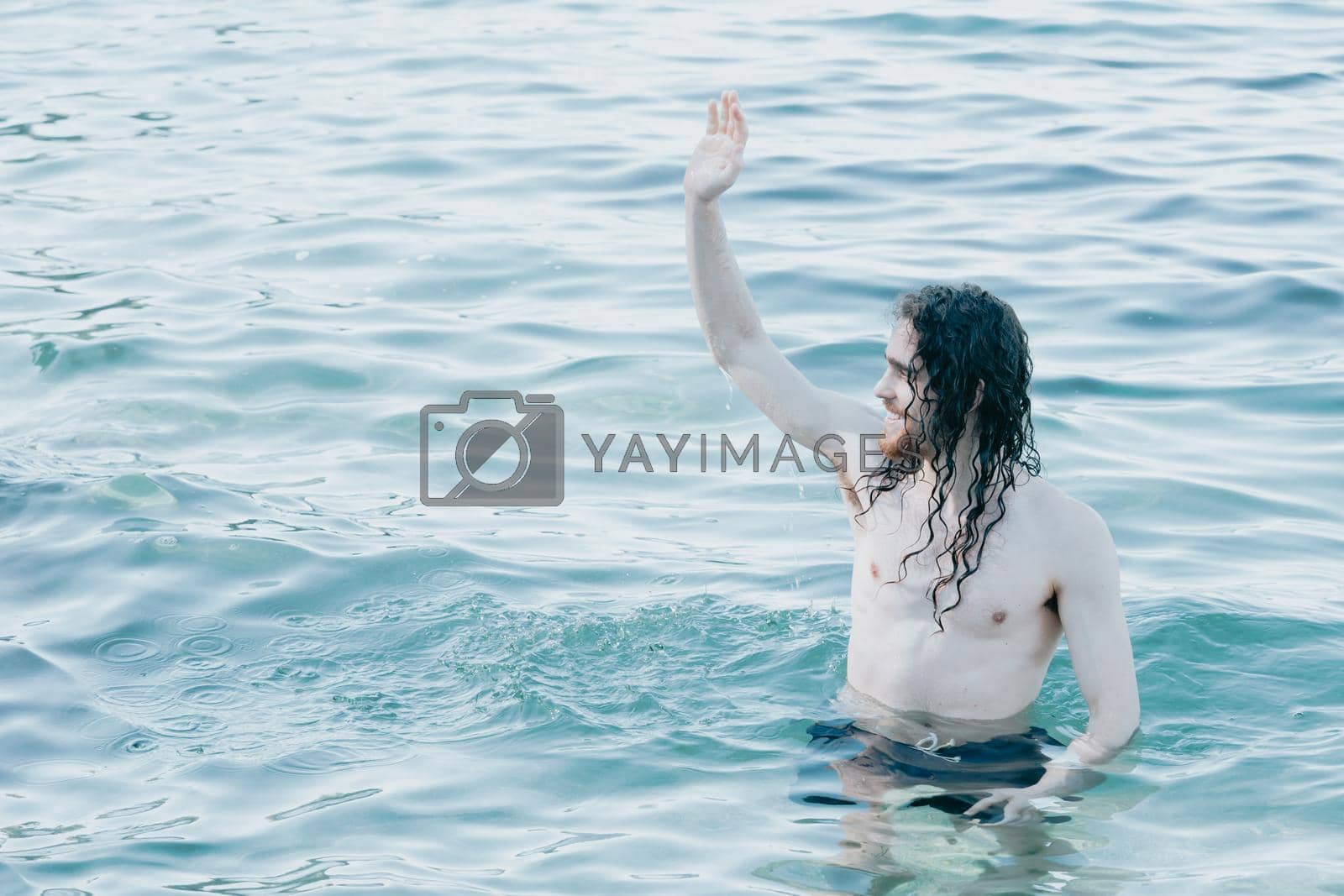 Royalty free image of Long hair man inside crystal clear water saluting someone in the beach, crystal clear water, holiday concept by AveCalvar