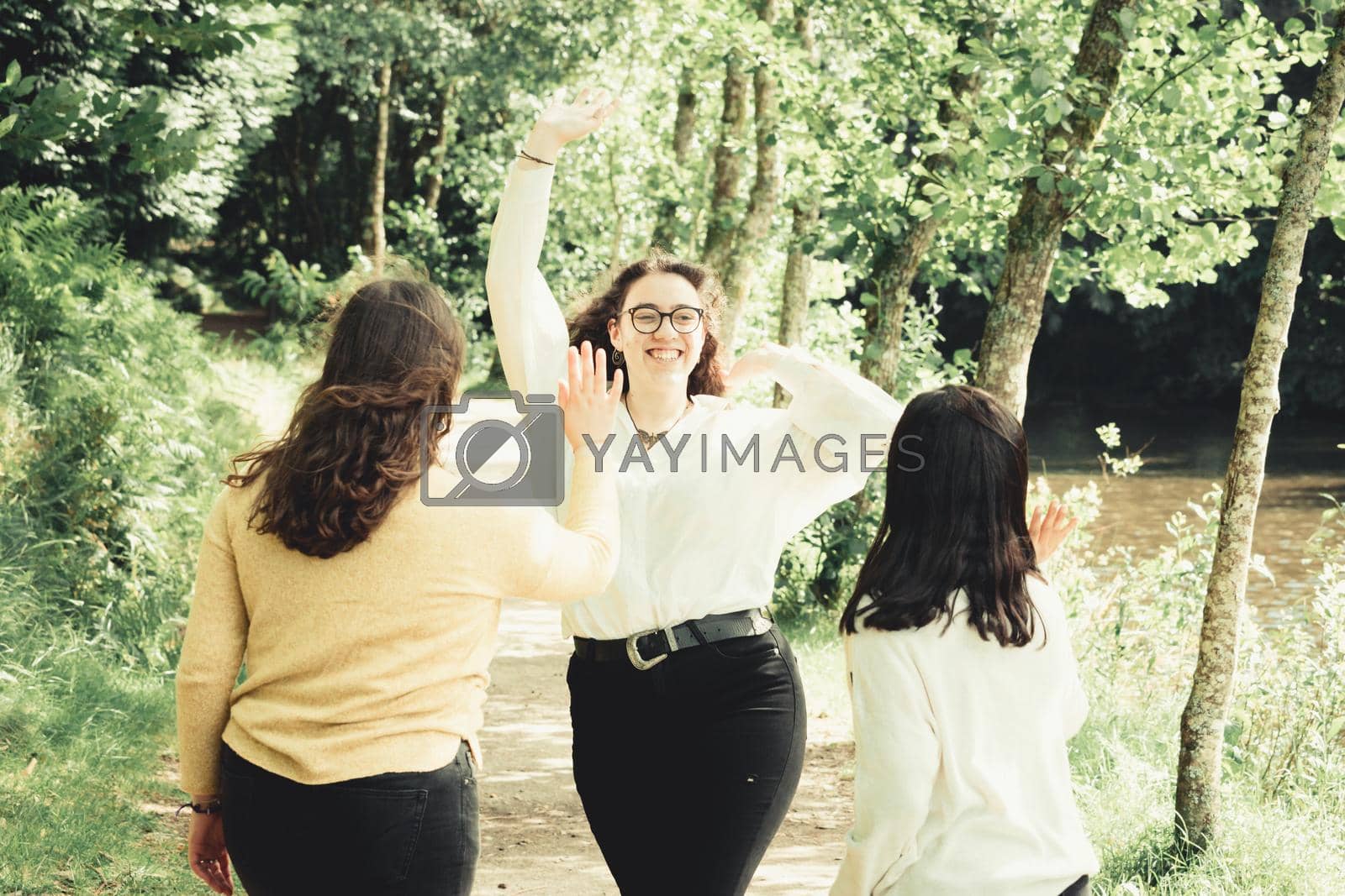 Royalty free image of One young woman about to high five two friends, friendship and fun concept, forest day, sunny by AveCalvar