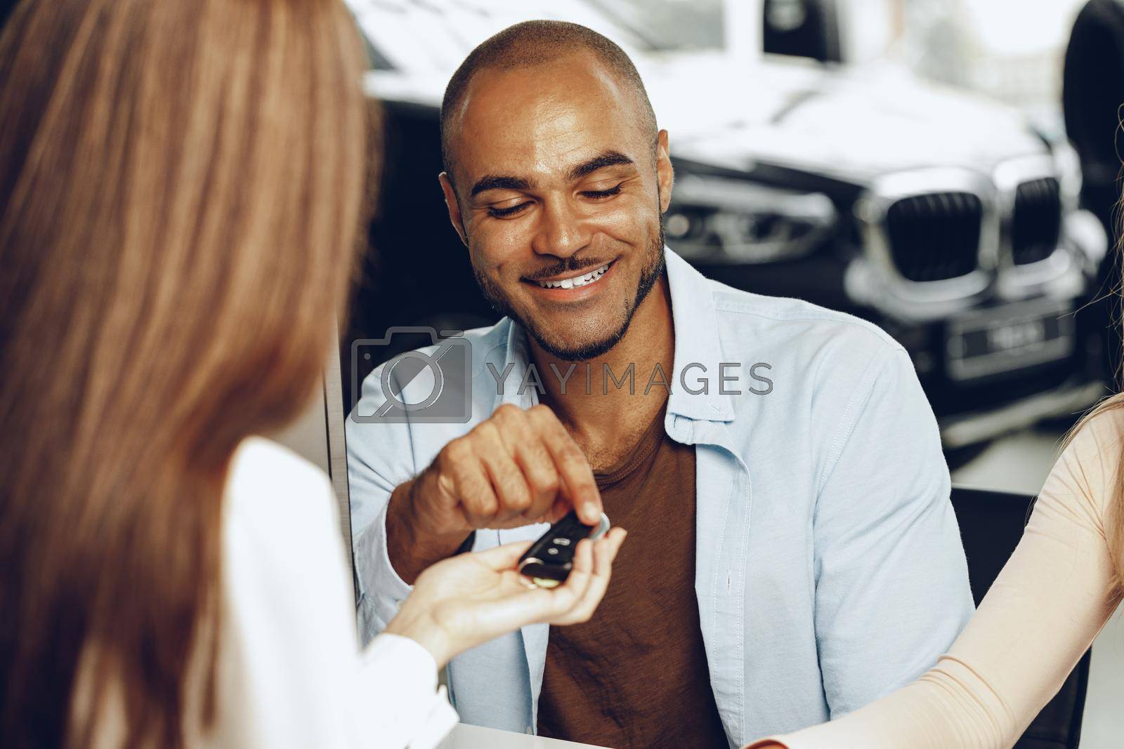 Royalty free image of Salesperson giving key to buyer in a car salon by Fabrikasimf