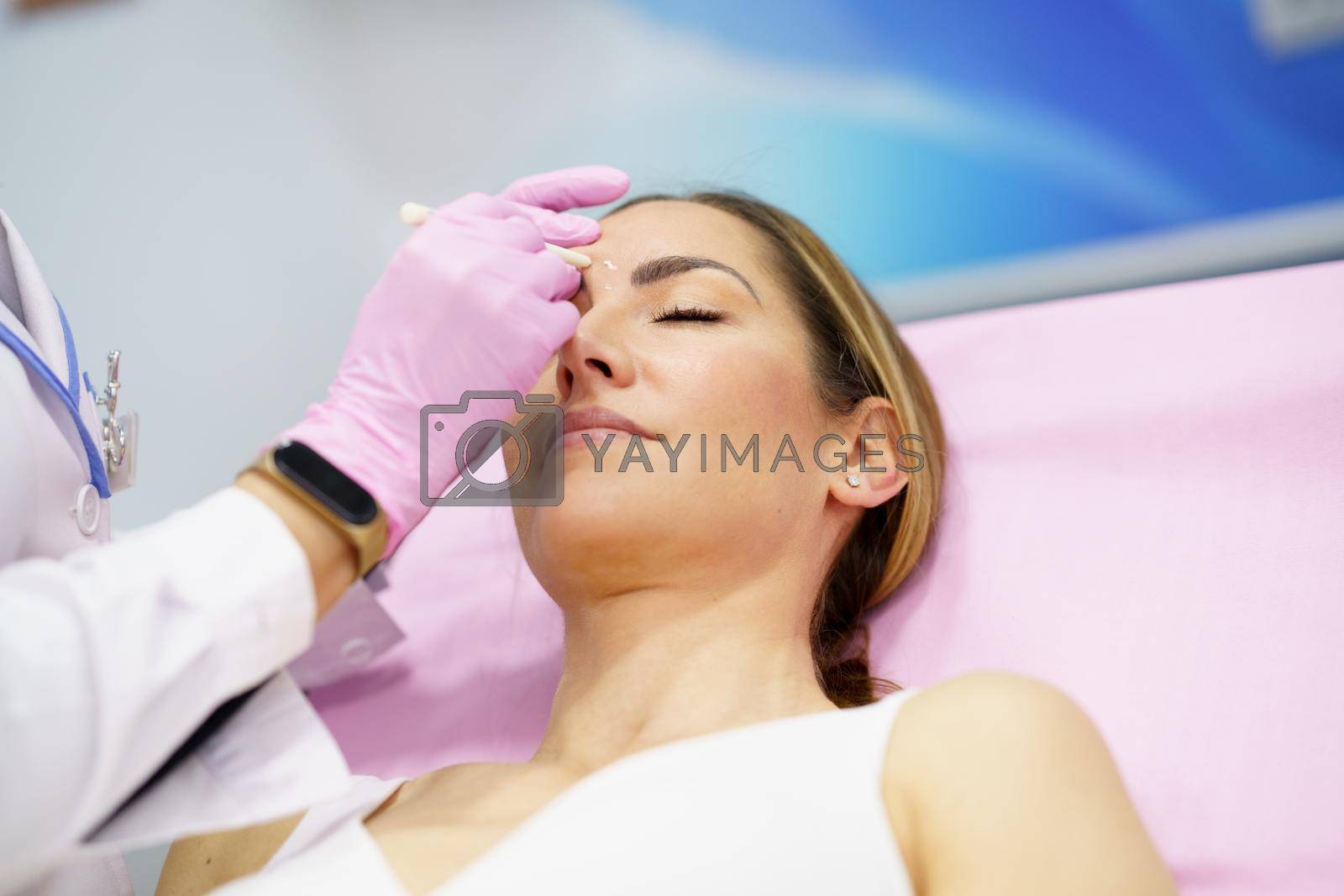 Royalty free image of Aesthetic doctor painting on the face of his patient the areas to be treated with botulinum toxin. by javiindy