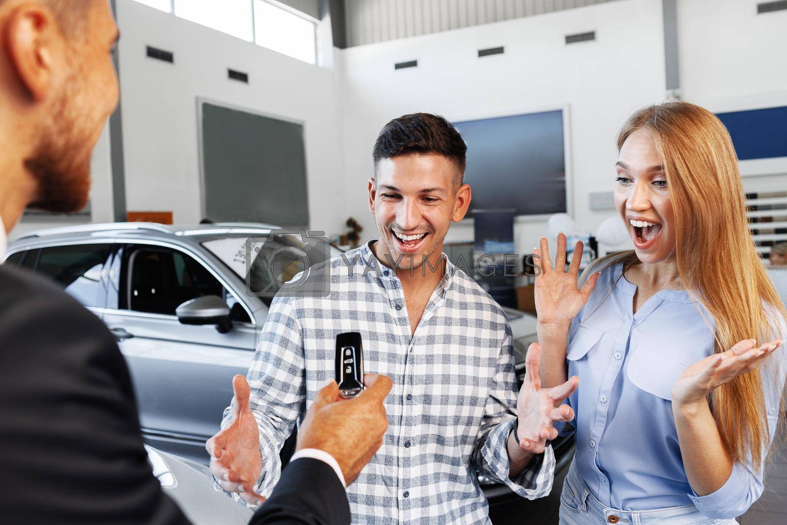 Royalty free image of Cherrful young couple at the dealership buying a new car by Fabrikasimf