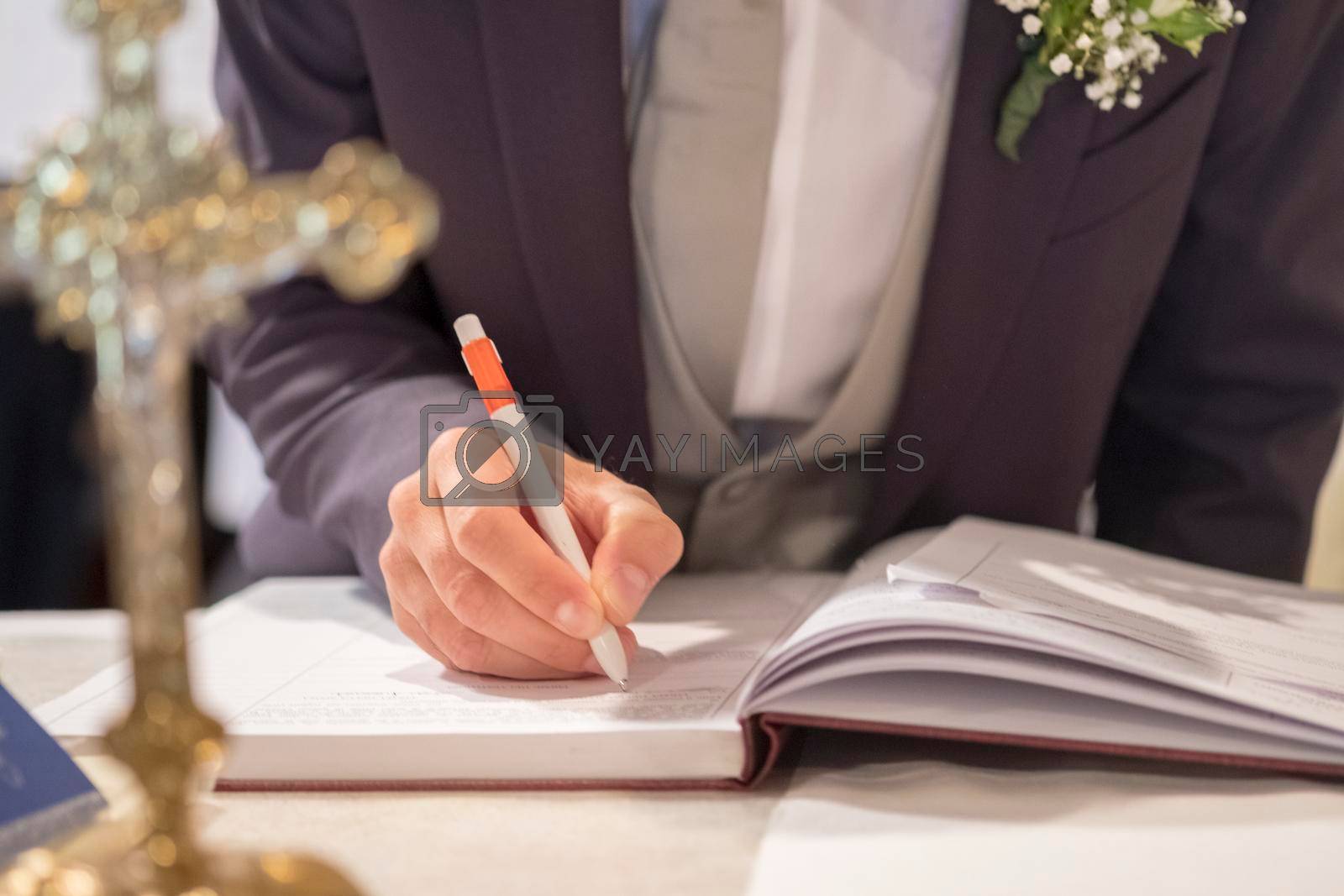 Royalty free image of wedding best man groom signing register in catholic wedding by tinofotografie