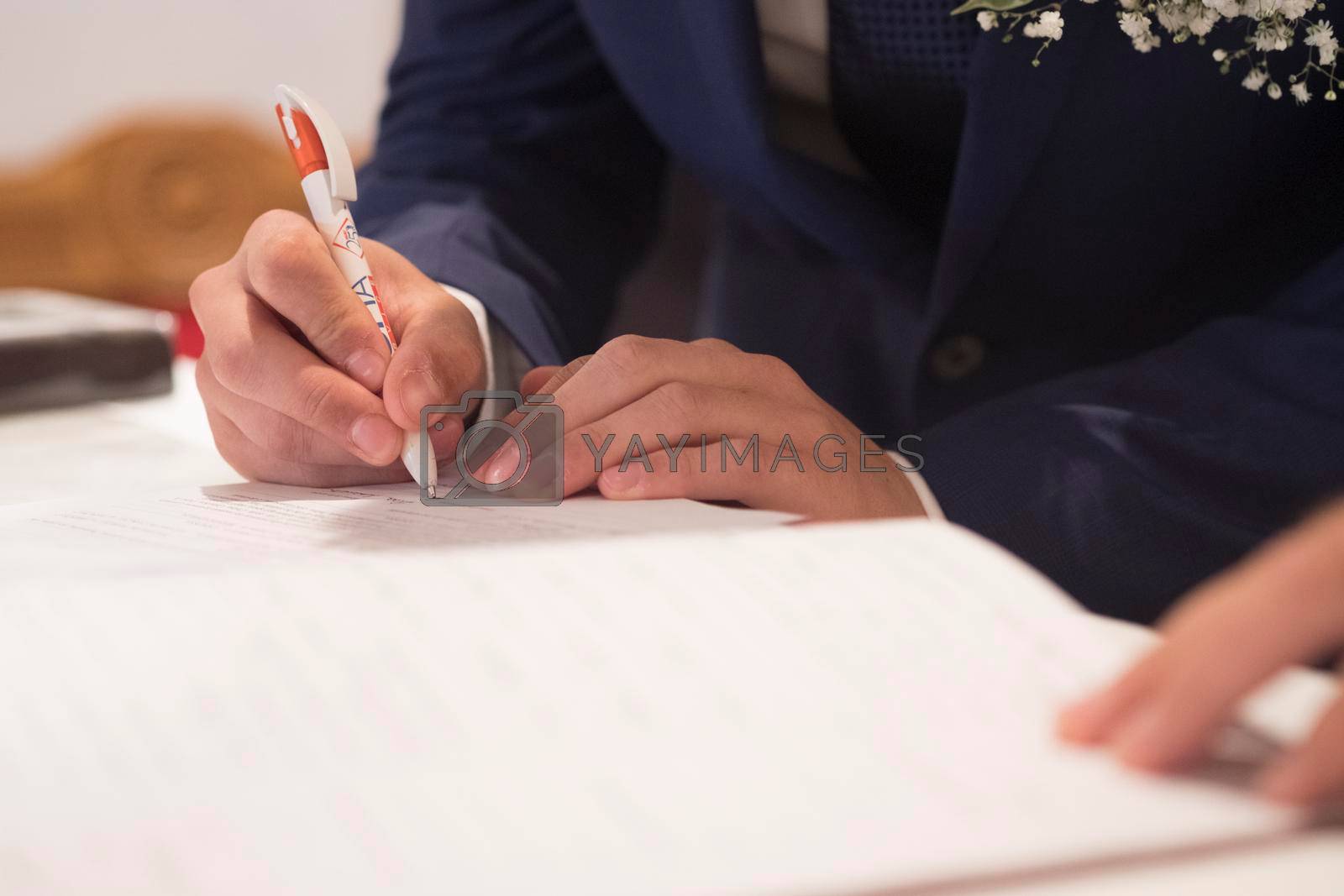 Royalty free image of wedding best man groom signing register in catholic wedding by tinofotografie