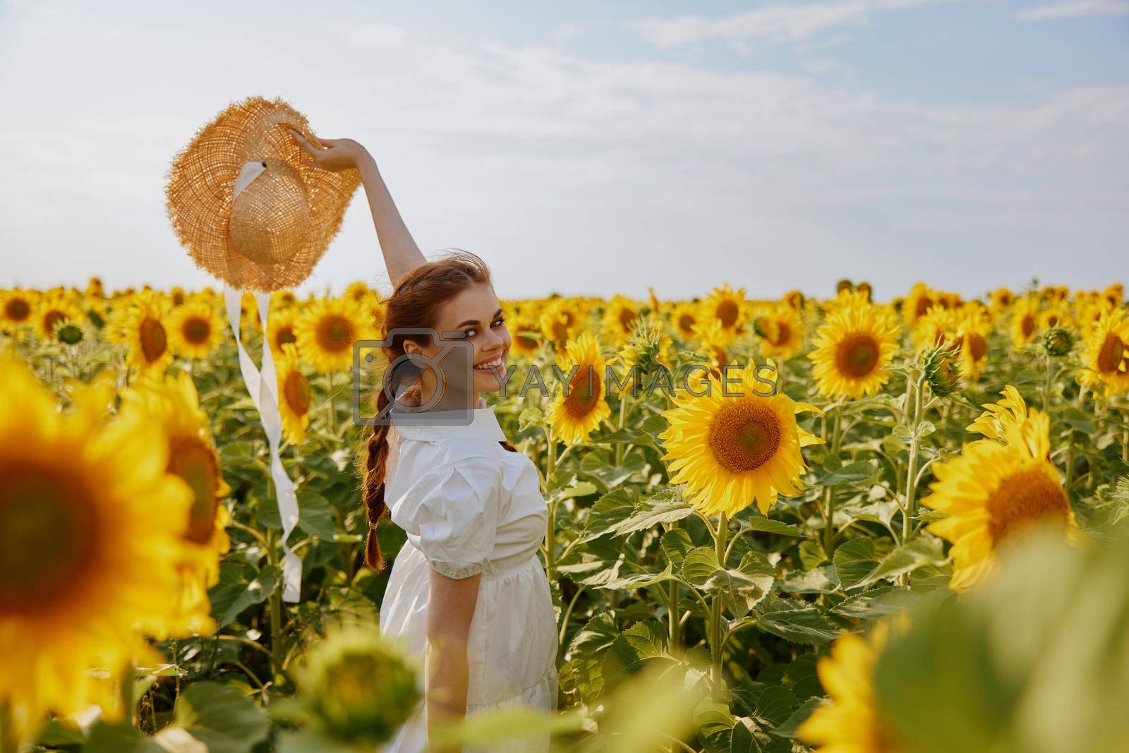 woman with raised up hands in a field of sunflowers straw hat landscape nature. High quality photo