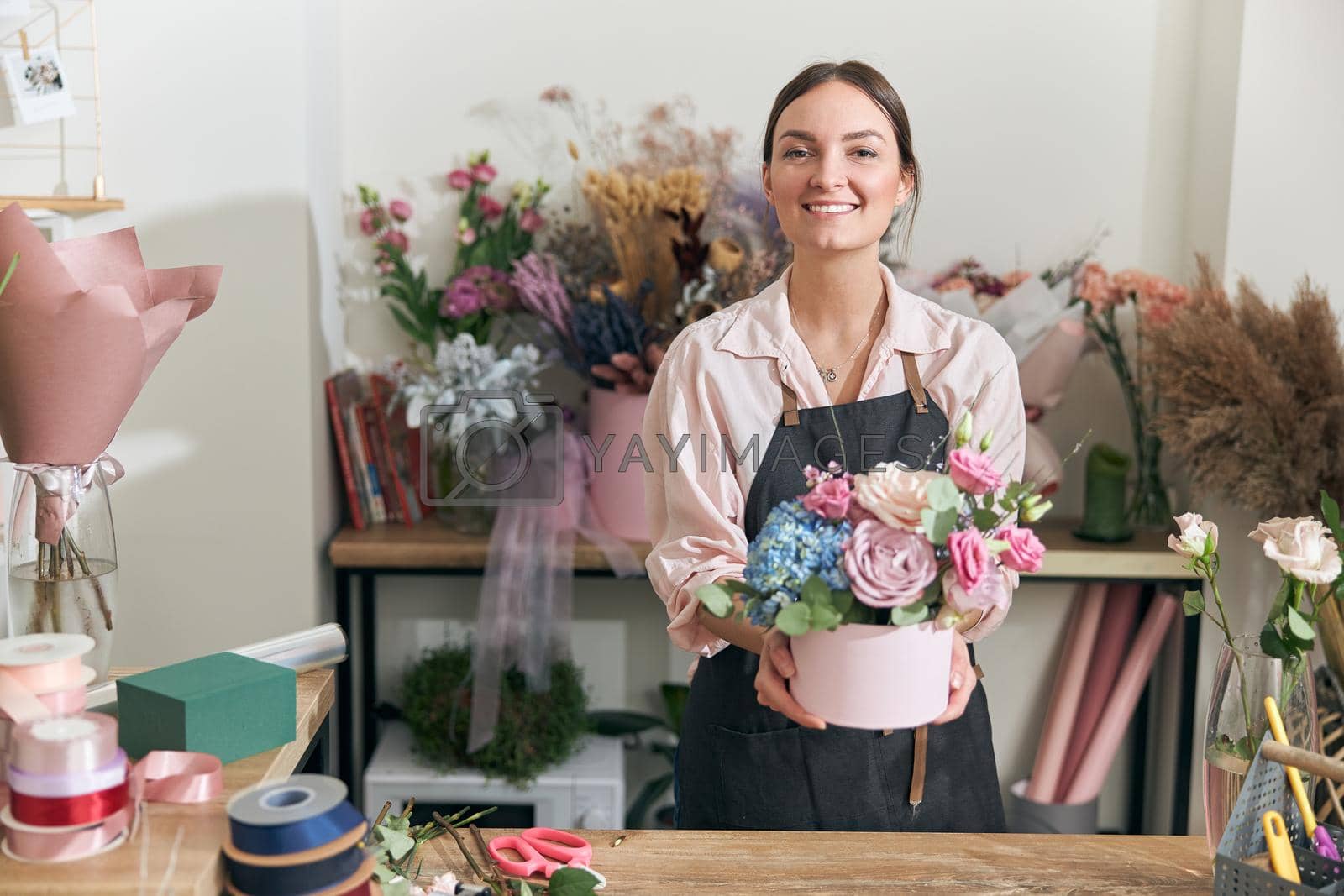 Royalty free image of Professional florist young woman is doing bouquets at flower shop by Yaroslav_astakhov