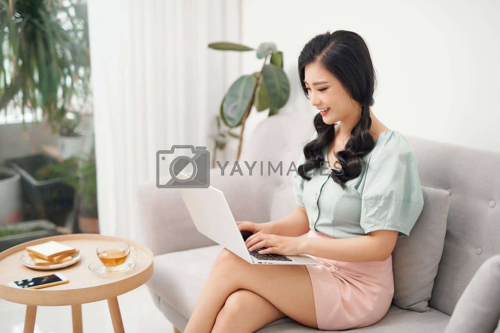 Royalty free image of Beautiful young Asia woman working with laptop in living room by makidotvn