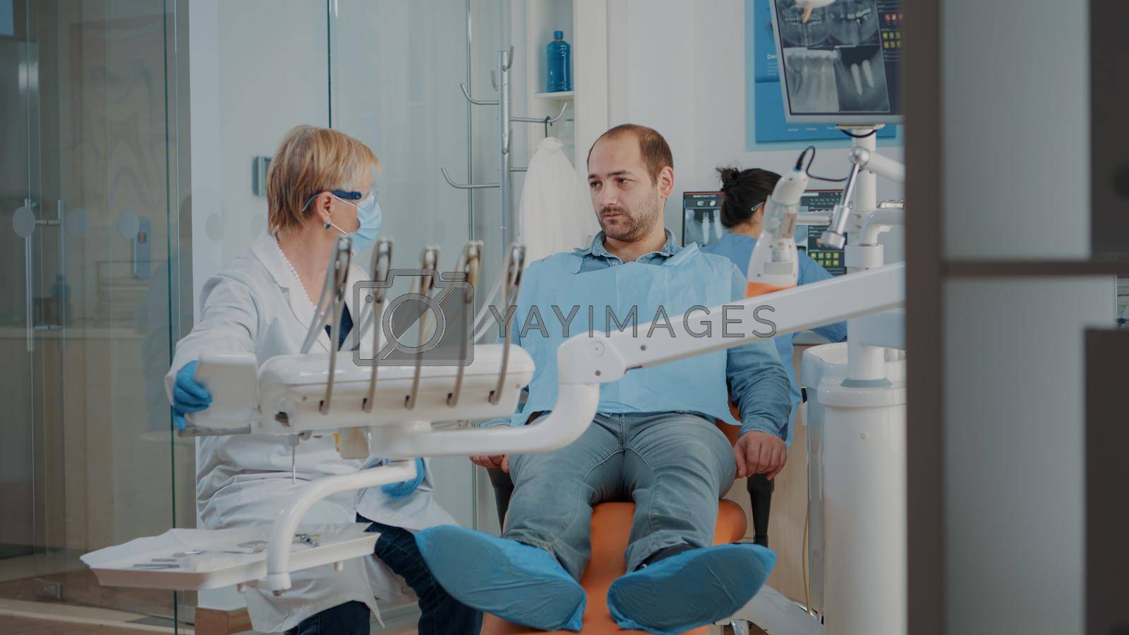 Stomatologist doing dental examination with orthodontic tools and instruments, treating patient with toothache. Dentist using drill and dentistry equipment at oral care examination.