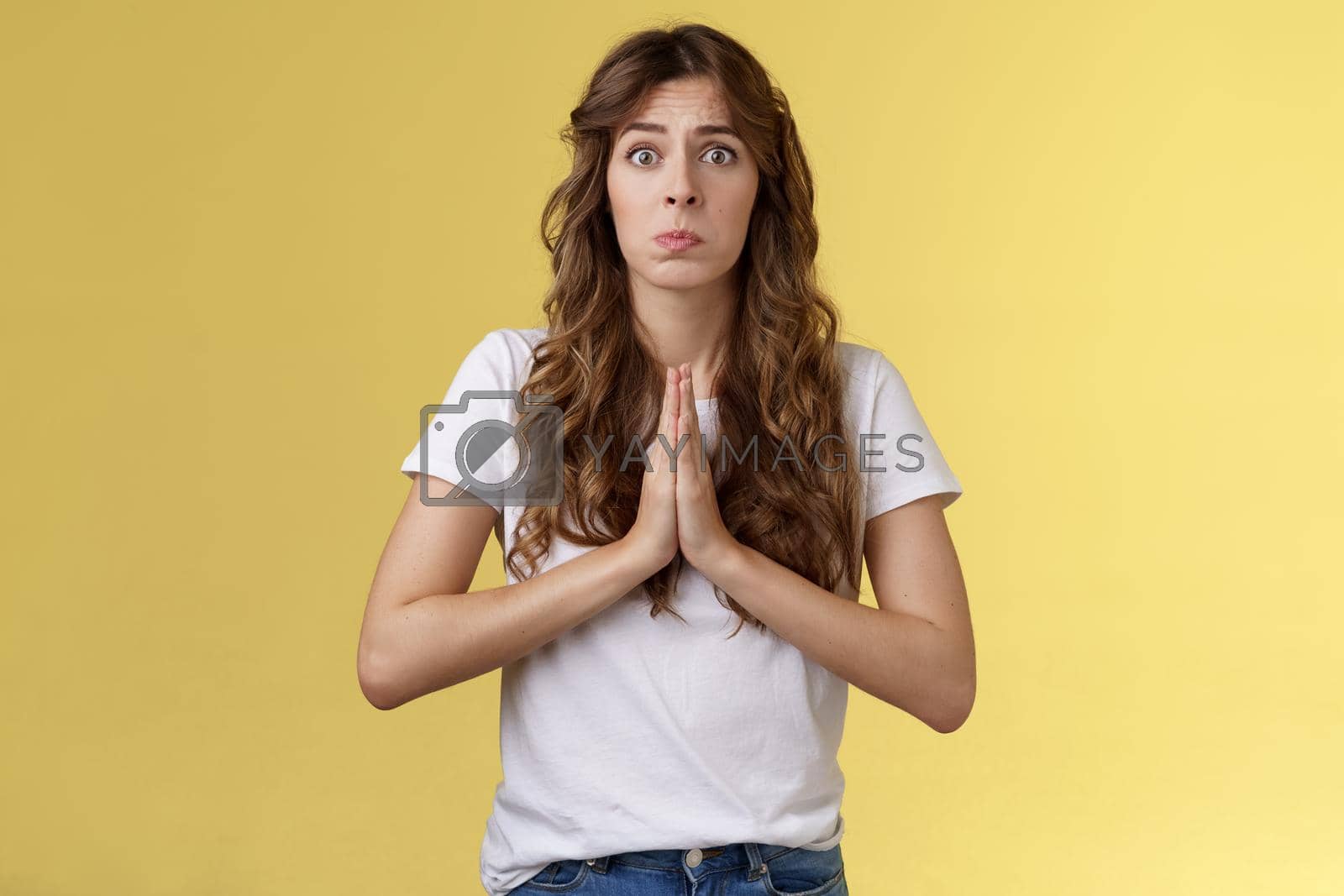 Royalty free image of Pretty please beg you help me. Innocent cute lovely upset caucasian girl begging pleading your mercy pulling face hope for pity apologizing puppy eyes frowning need urgent advice yellow background by Benzoix