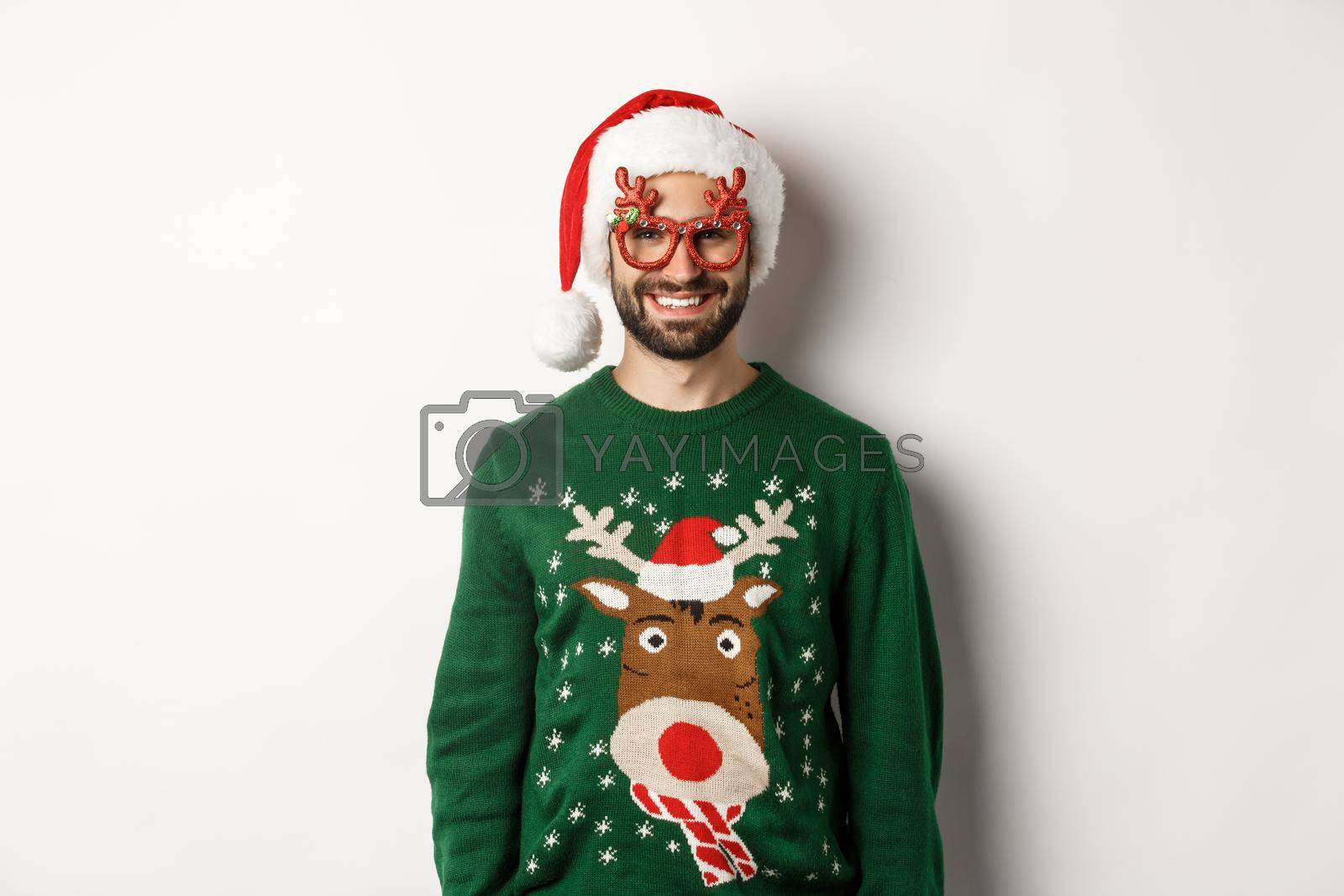 Christmas holidays, celebration concept. Happy man in Santa hat and funny party glasses standing against white background.