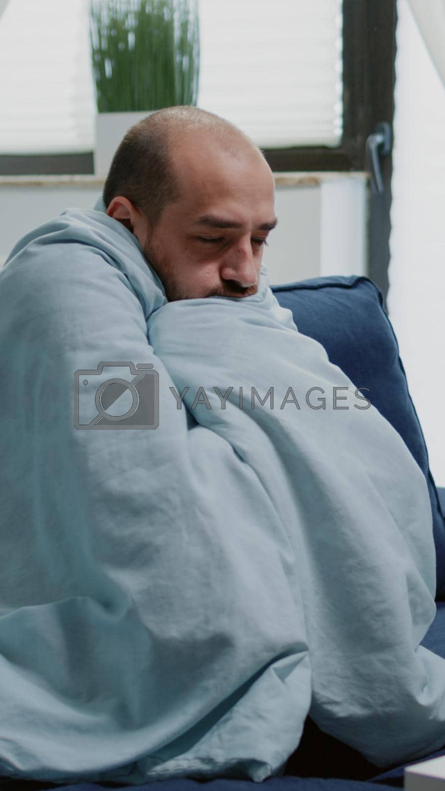 Royalty free image of Person with flu feeling cold and shivering wrapped in blanket by DCStudio