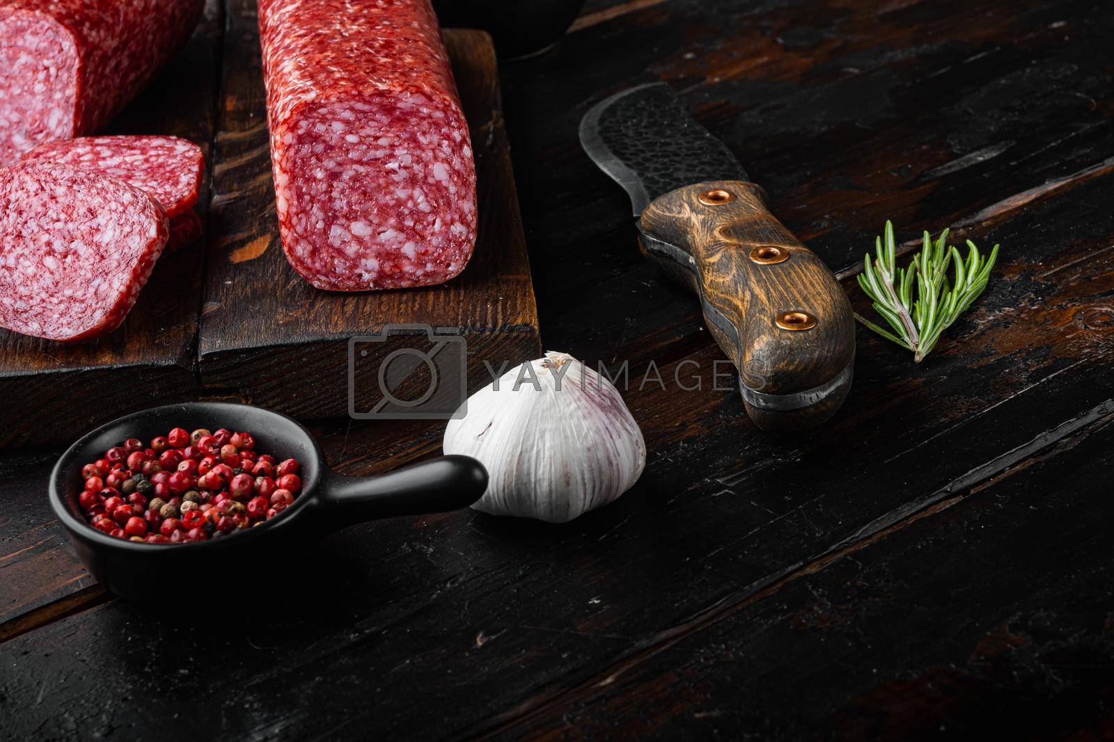 Royalty free image of Salami with ingredients, on old dark wooden table background, with copy space for text by Ilianesolenyi