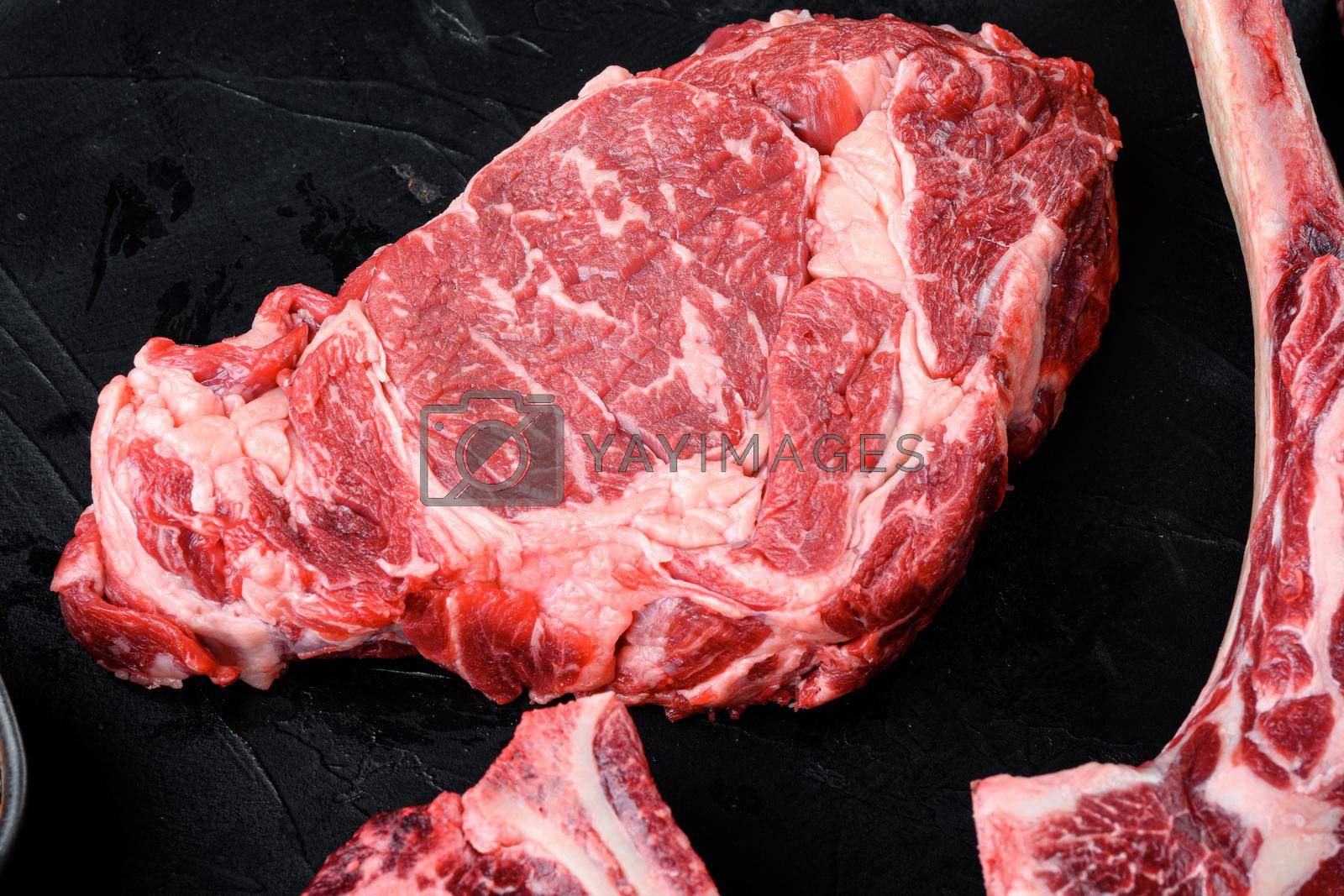 Royalty free image of Raw fresh marbled meat Steak Ribeye. Black Angus Rib eye, on black stone background, top view flat lay by Ilianesolenyi