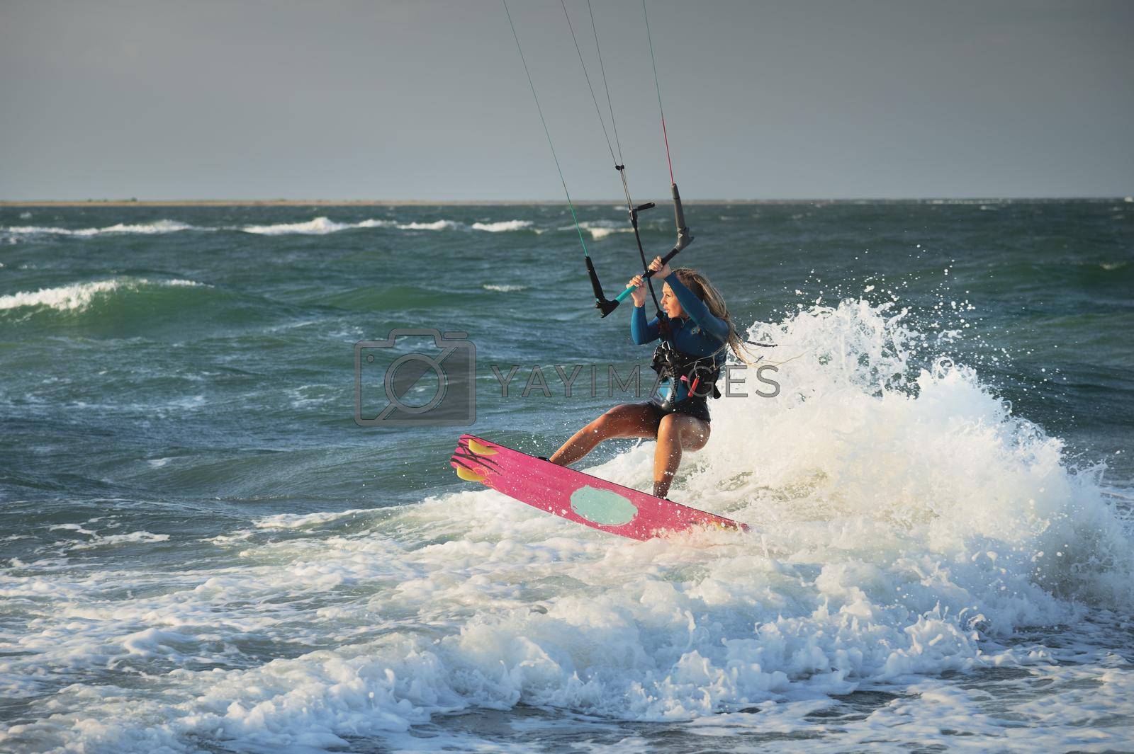 Royalty free image of Professional kitesurfer caucasian woman rides big waves in windy weather. Kitesurfing by yanik88